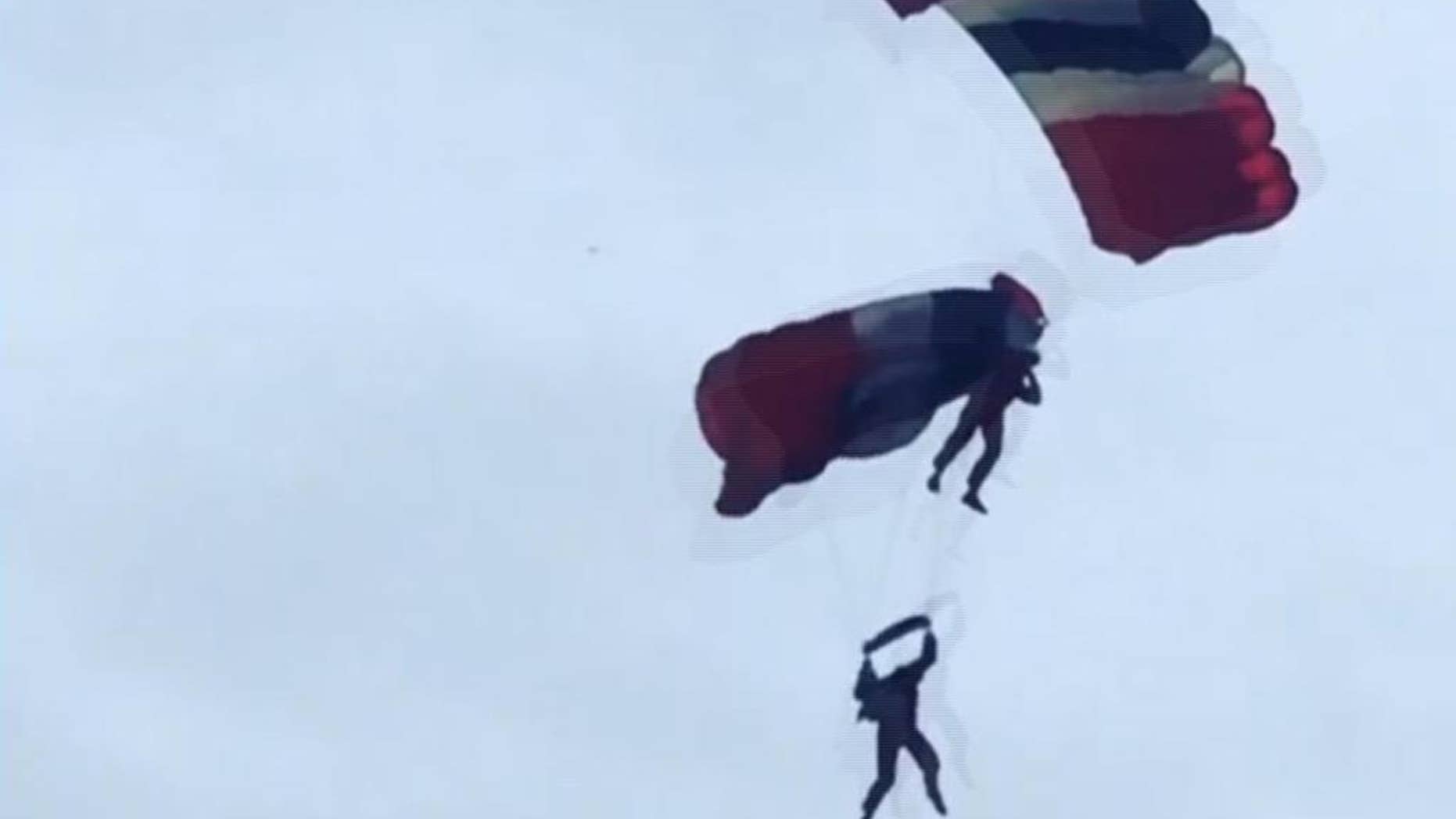 This image taken from video provided by Ricky Parnaby shows a member of the British military stunt team, The Red Devils, receiving assistance from a teammate after his parachute failed to open properly whilst performing Friday, June 19, 2015 at the Whitehaven Airshow in northwestern England. A message posted on the show's Facebook page assured spectators that both were fine after "one team member caught his teammate and brought him into Queens Dock." The parachutists landed in water and were plucked to safety. (Ricky Parnaby via AP) MANDATORY CREDIT