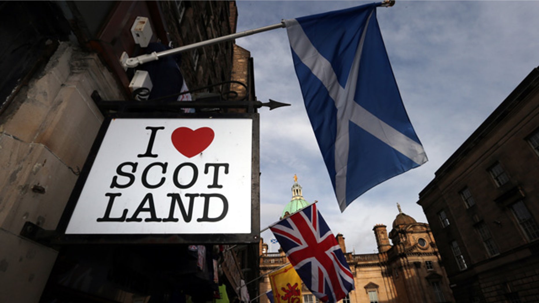 FILE - In this Thursday, Feb. 13, 2014, file photo a Scottish flag and a Union flag fly outside a Scottish memorabilia shop in Edinburgh, Scotland. (AP Photo/Scott Heppell, File)