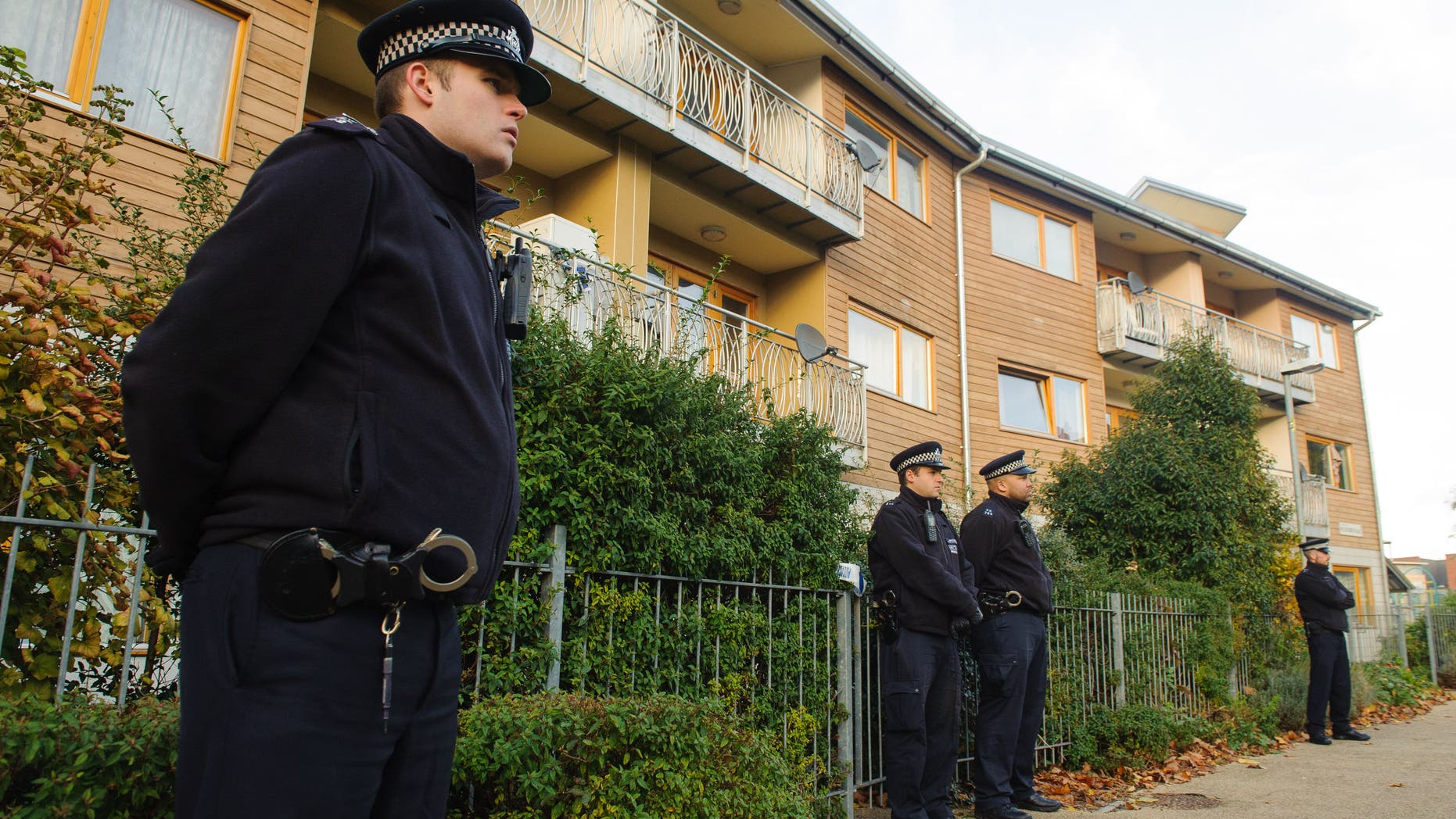 Nov. 23, 2013: Police officers stand outside flats as police conduct house-to-house inquires in the area where three women were rescued in south London.