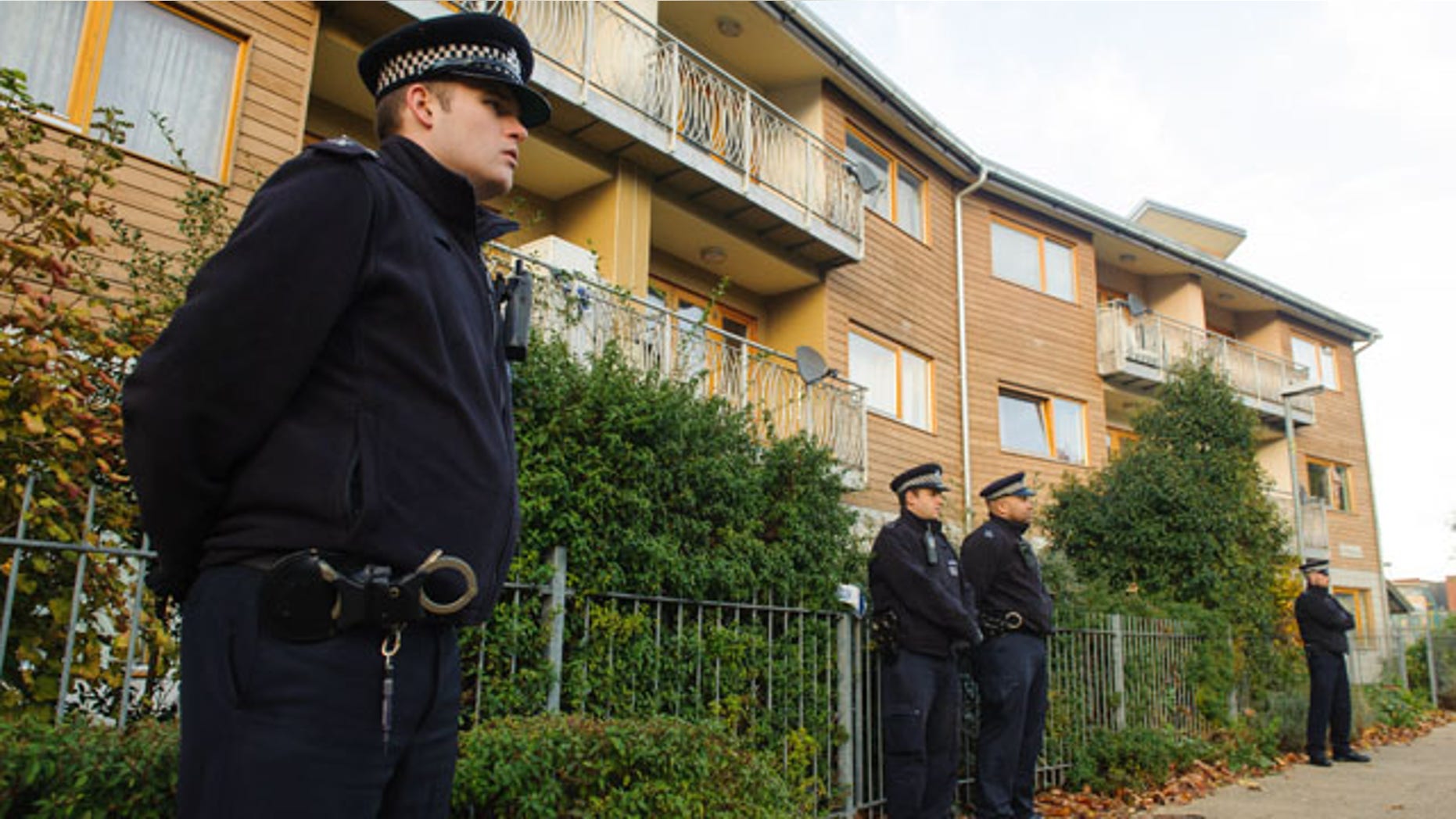 November 23, 2013: Police officers stand outside flats as police conduct house-to-house inquires in the area where three women were rescued in south London. UK police said Saturday that a collective living situation based on shared political beliefs is at the root of a major slavery case that led to the arrest of two suspects this week.
