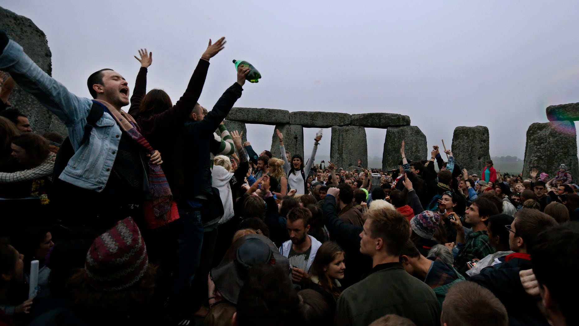 June 21, 2013 - People dance and raise their hands in celebration during the summer solstice shortly after 04.52 am at the prehistoric Stonehenge monument, near Salisbury, England, Friday. Following an annual all-night party, thousands of new agers and neo-pagans waited at the ancient stone circle Stonehenge for the sun to come up, but cloudy skies prevented them. They danced and whooped in delight .