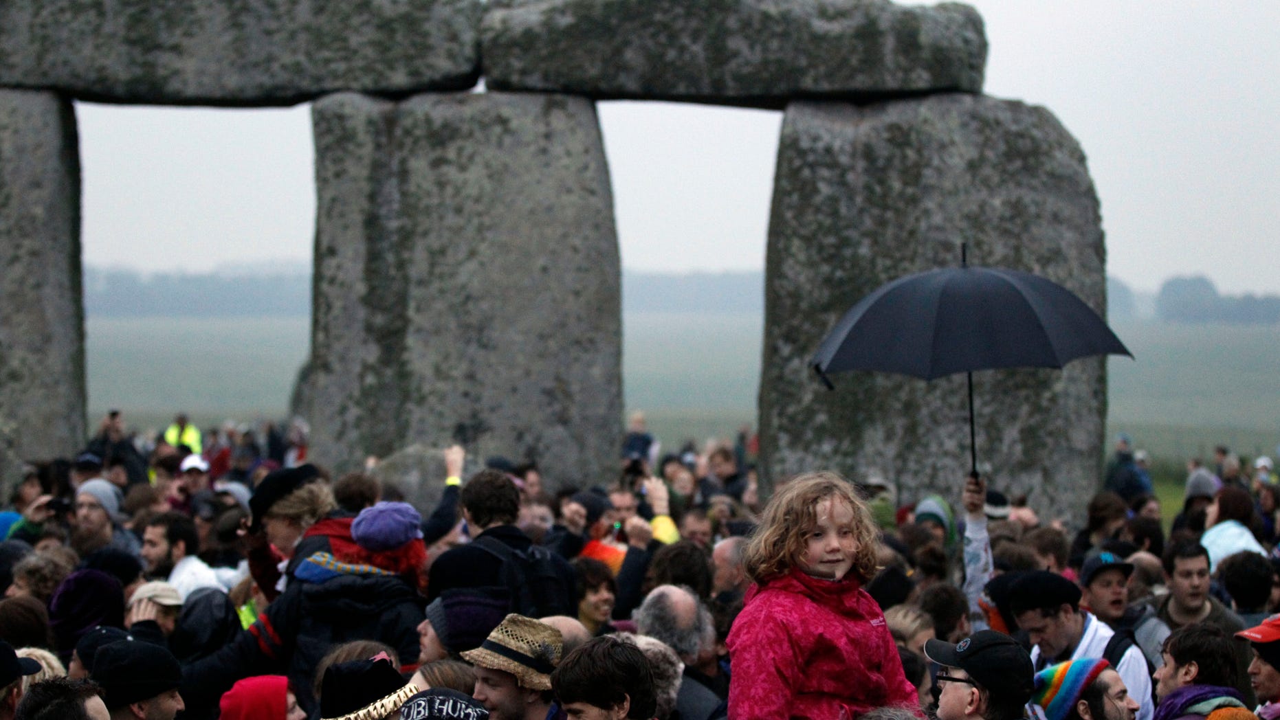 People gather during the summer solstice at Stonehenge, near Salisbury Thursday, June 21, 2012. Rain-sodden crowds welcomed a spectacularly rainy summer solstice at Stonehenge in true British fashion Thursday: With stoicism and wit. But through the wind and rain, drummers inside the ancient stone circle kept up their thumping rhythm, new age pagans kept up their chaotic dance, and visitors kept up their sense of humor. (AP Photo/Lefteris Pitarakis)
