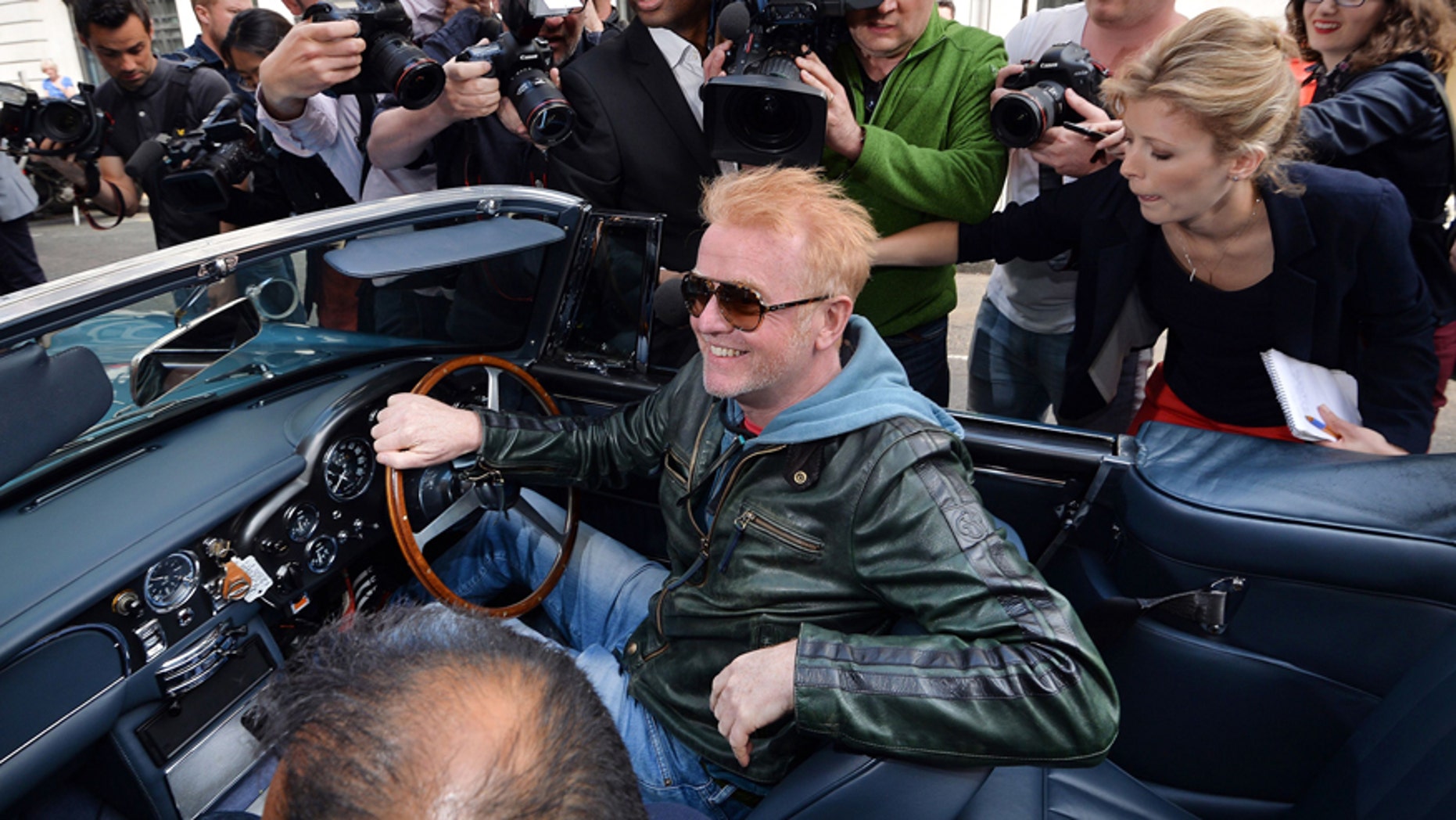 Media flock around radio and TV personality, Chris Evans as he leaves the BBC Radio studios in London, Wednesday June 17, 2015, driving his vintage Aston Martin car, after he was announced as the new Top Gear presenter. The BBC TV company says its top automotive TV show "Top Gear" will return to the airwaves with Chris Evans as the new host, replacing scandal-tainted Jeremy Clarkson, who was sacked for punching one of the show's producers. (John Stillwell / PA via AP) UNITED KINGDOM OUT - NO SALES - NO ARCHIVES