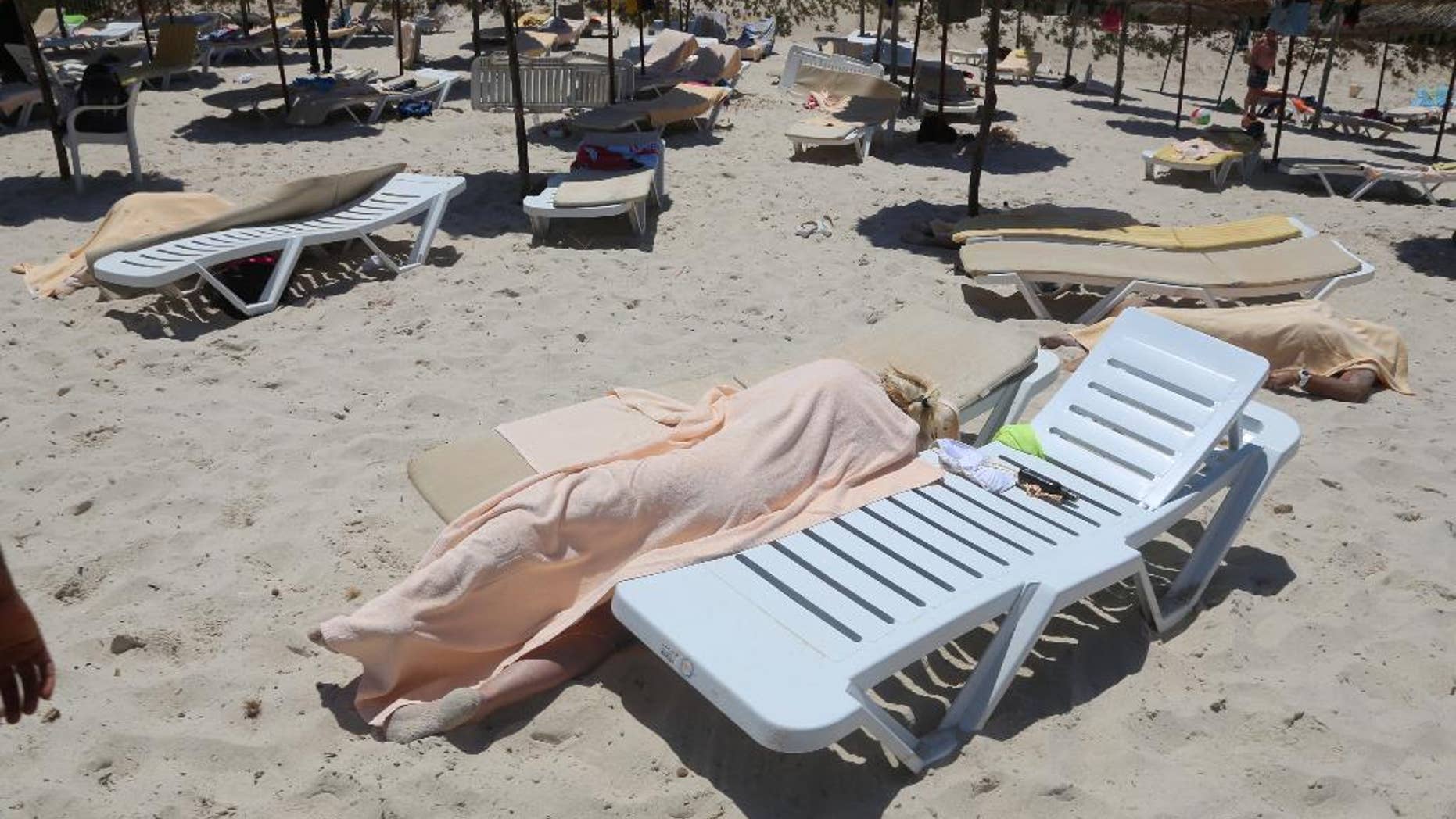 FILE - In this Friday, June 26, 2015 file photo, bodies are covered on a Tunisian beach, in Sousse. The British government on Thursday, July 9, 2015 told all U.K. tourists to leave Tunisia because a terrorist attack is "highly likely" and the North African country's government has not done enough to enhance security. (Jawhara FM via AP, File)