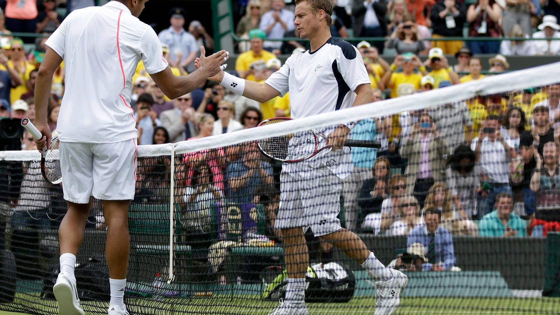 June 26, 2012: Jo-Wilfried Tsonga of France, left, shakes hands with Lleyton Hewitt of Australia after defeating him during a first round men's singles match at the All England Lawn Tennis Championships at Wimbledon, England.