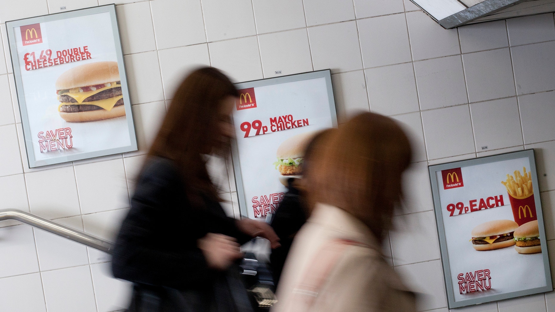 April 30, 2012: Three women walk past an advert for McDonald's fast food restaurant products in London.