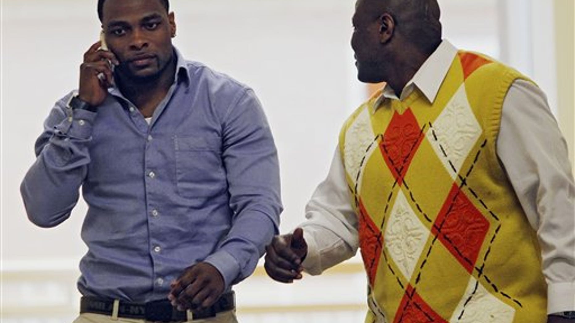 March 1: Former Denver Broncos cornerback Perrish Cox, left, talks on his phone as he walks the hallway with his uncle, Ron Davis, outside the courtroom in Castle Rock, Colorado.