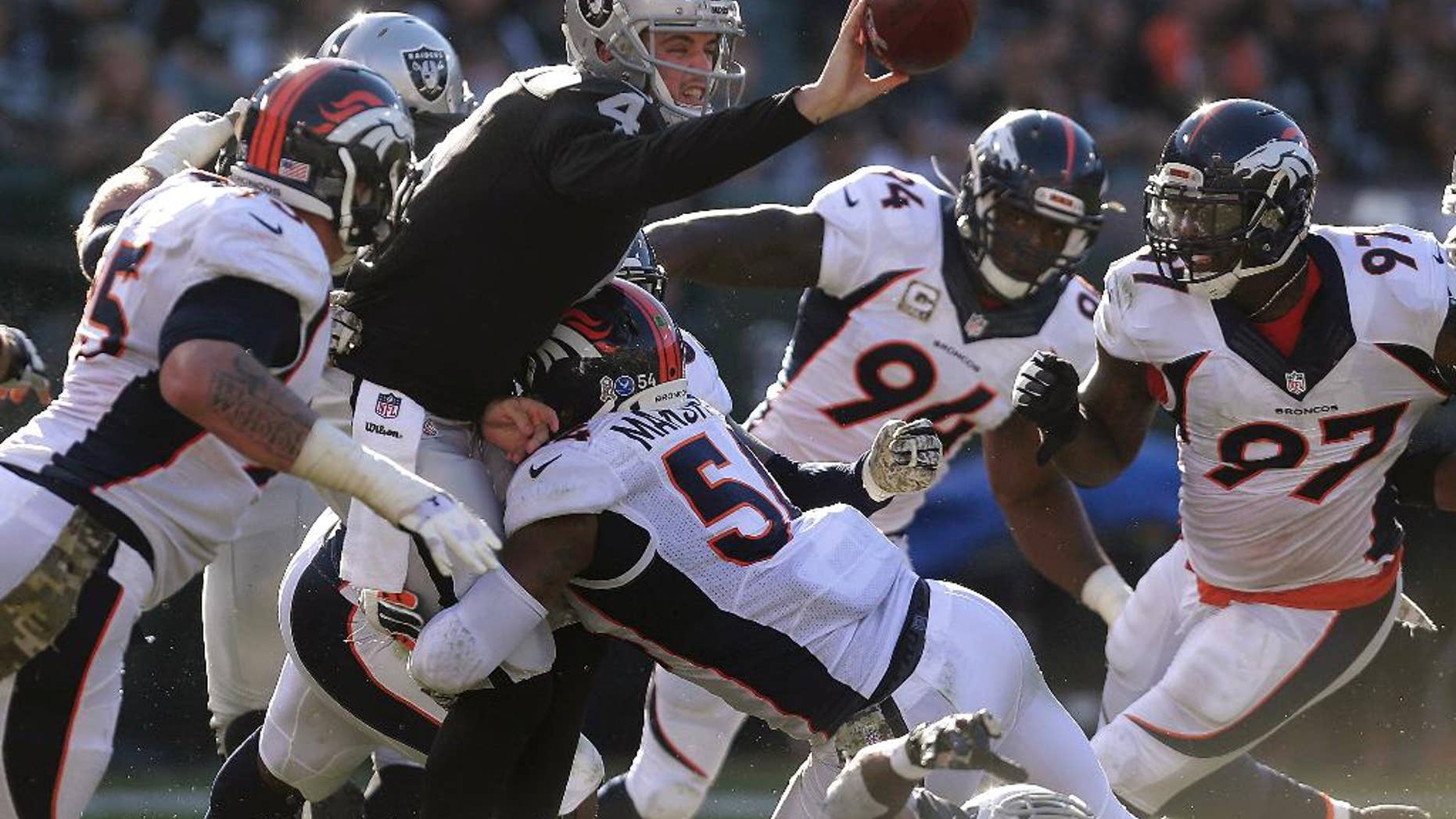 Oakland Raiders quarterback Derek Carr (4) gets rid of the ball as he is pressured by Denver Broncos linebacker Brandon Marshall (54) during the third quarter of an NFL football game in Oakland, Calif., Sunday, Nov. 9, 2014. Carr threw the ball to offensive tackle Khalif Barnes, who fumbled; the ball was recovered by Broncos cornerback Chris Harris. (AP Photo/Marcio Jose Sanchez)