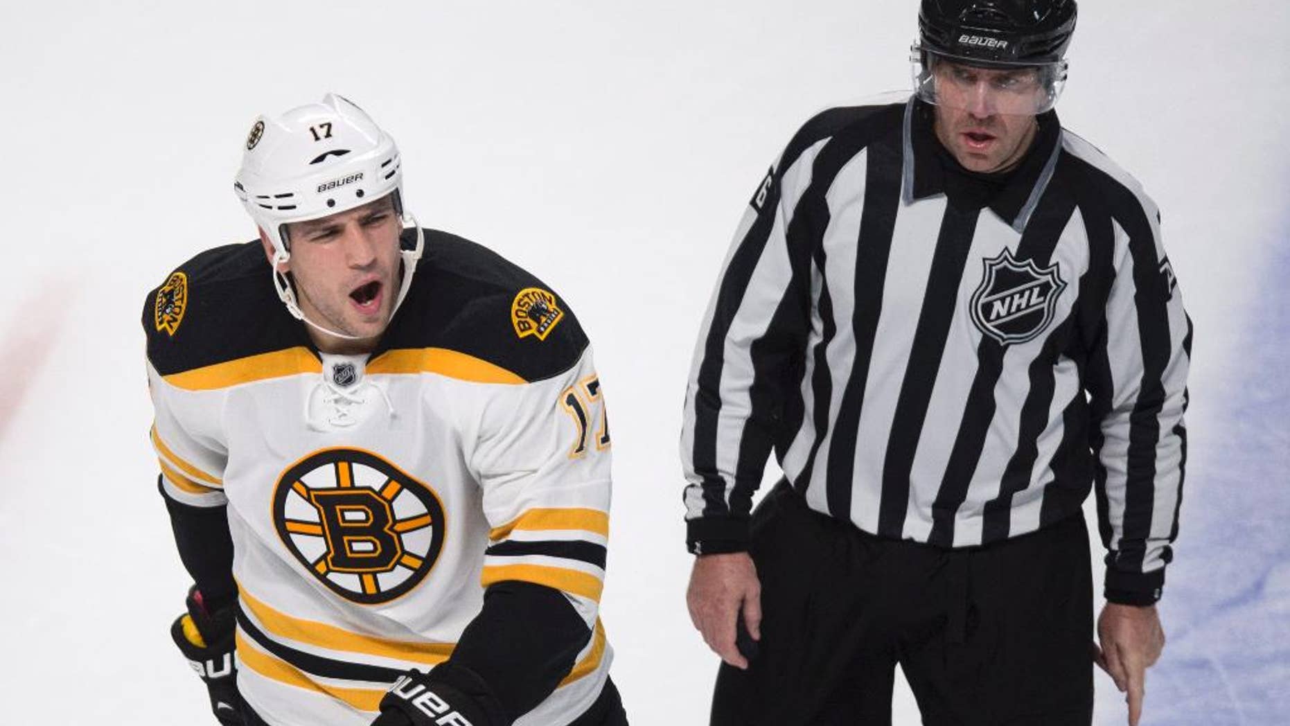 Boston Bruins' Milan Lucic, left, reacts as he is escorted off the ice by linesman Michel Cormier after receiving a penalty near the end of an NHL hockey game against the Montreal Canadiens, Thursday, Oct. 16, 2014, in Montreal. The Canadiens won 6-4. (AP Photo/The Canadian Press, Paul Chiasson)