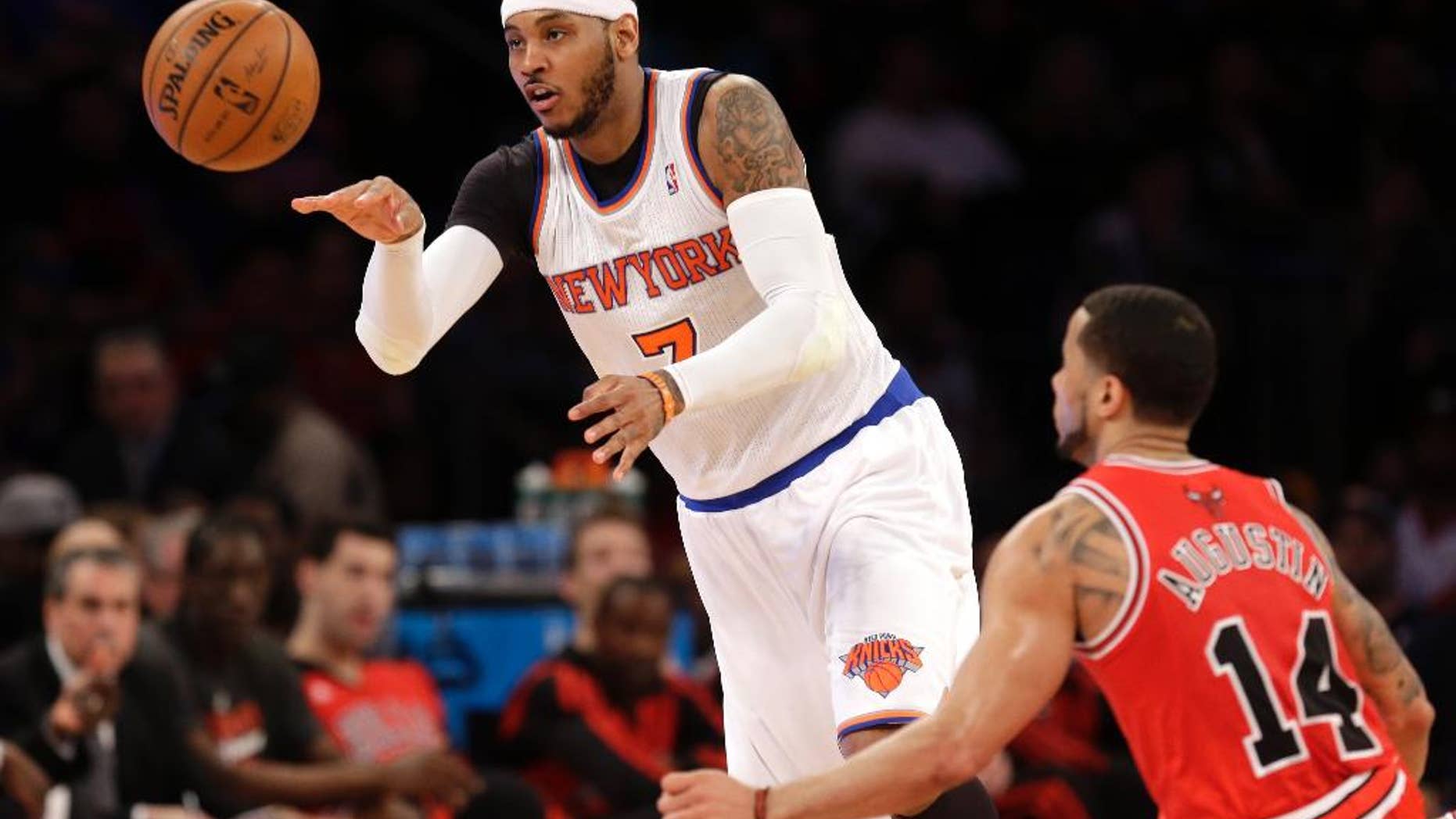 New York Knicks' Carmelo Anthony, left, passes the ball past Chicago Bulls' D.J. Augustin during the first half of the NBA basketball game, Sunday, April 13, 2014 in New York. The Knicks defeated the Bulls 100-89. (AP Photo/Seth Wenig)