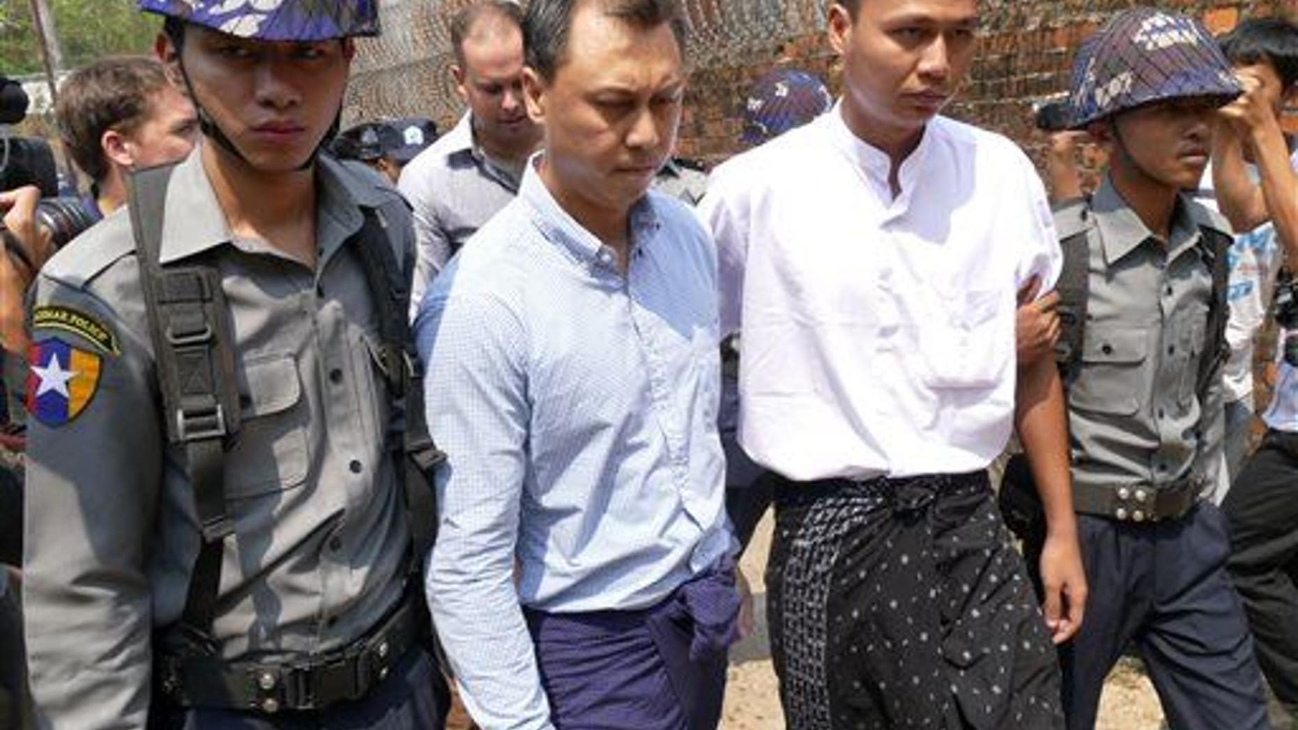 V Gastro bar owner Tun Thurein, second from left, and employee Htut Ko Ko Lwin, second from right, are escorted by Burma police officers at a township court Tuesday, March 17, 2015, in Yangon.