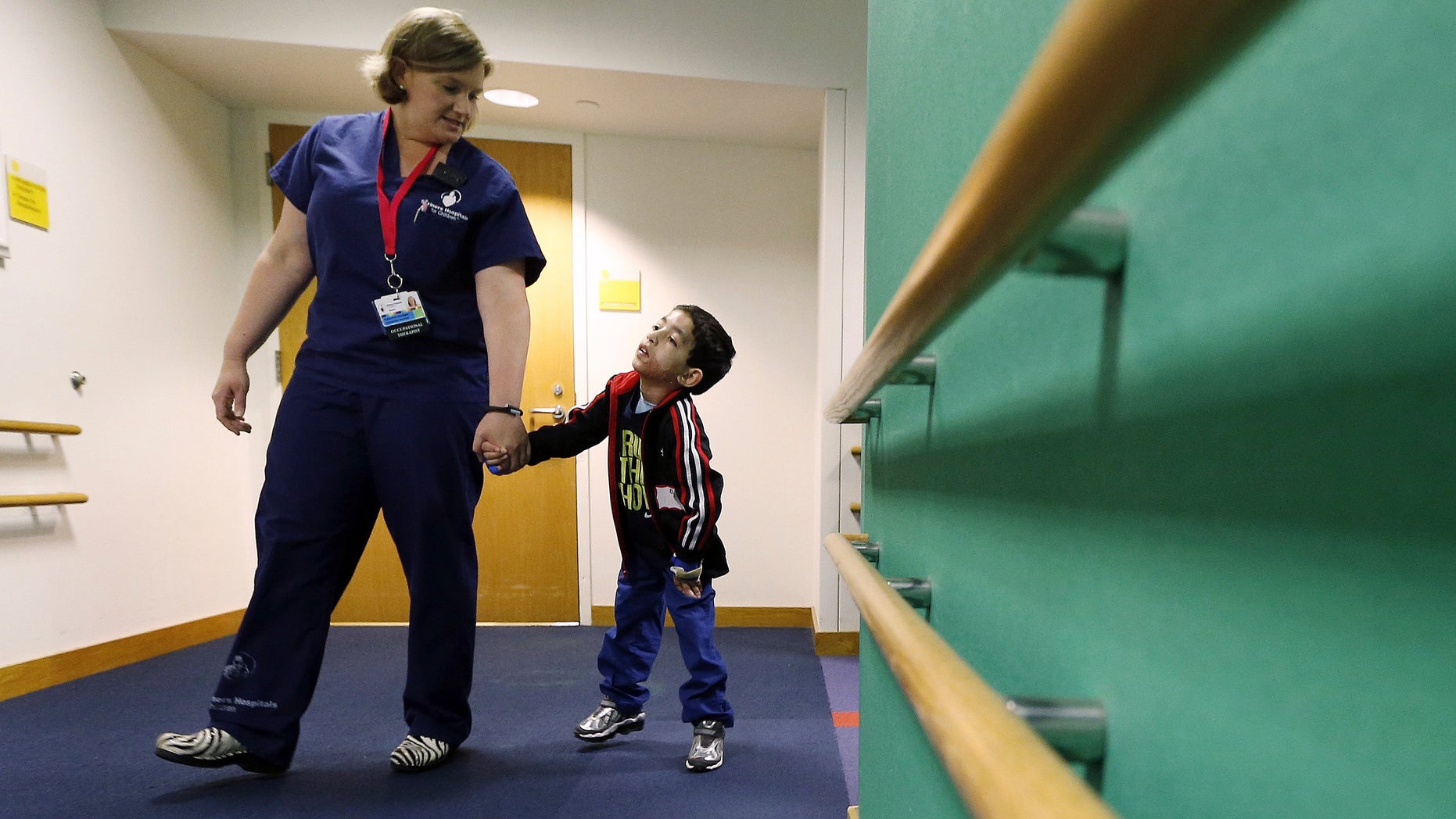 Therapist Katherine Hartigan walks with Ihor Lakatosh at Shriners Hospital for Children in Boston. (AP Photo/Michael Dwyer)