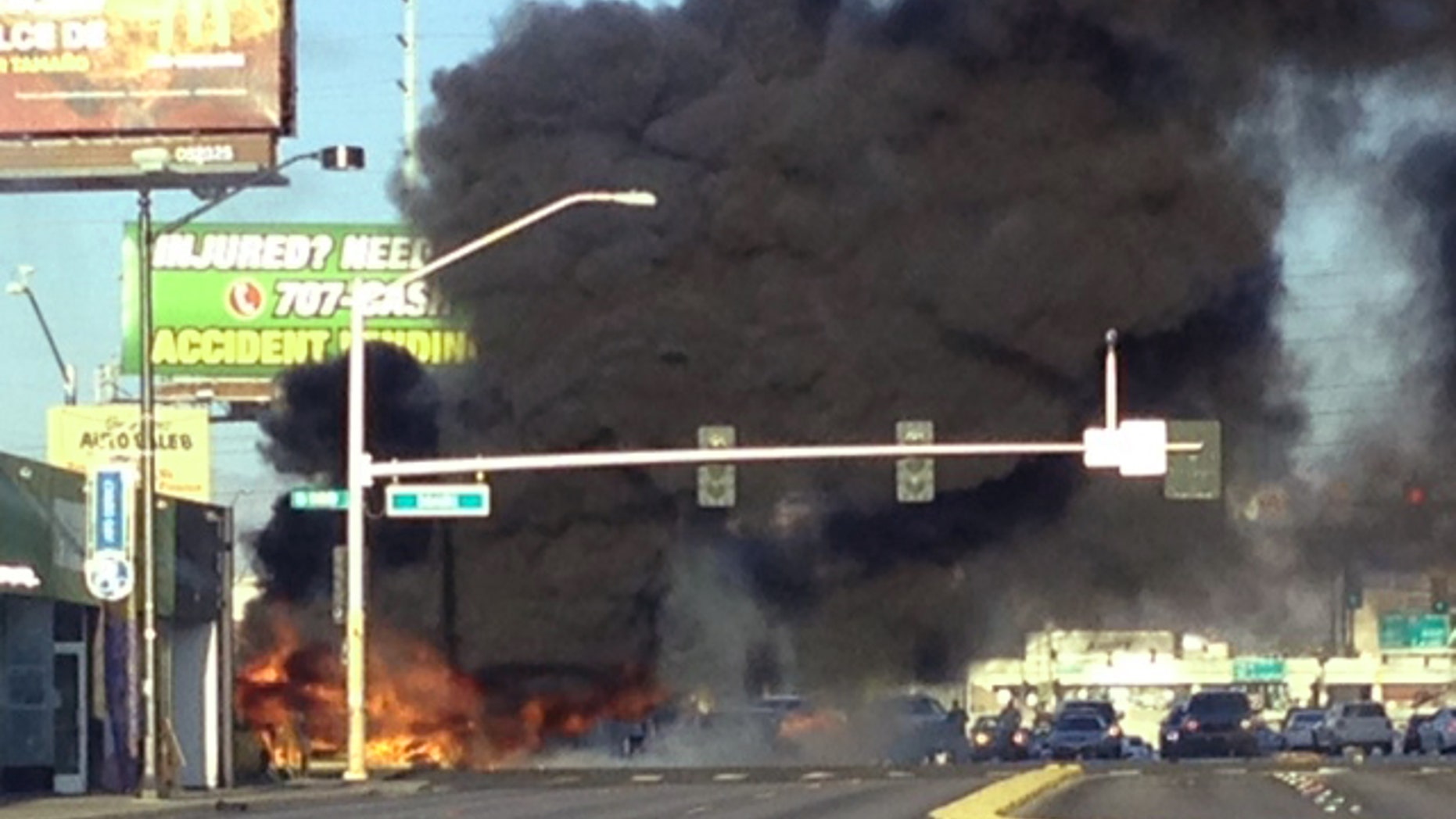 Smoke filled the sky after a fire tore through a mini bus following a collision in Las Vegas, on Saturday, Sept. 5, 2015. Fire officials say a burning mini bus was found lying on its side on the sidewalk and a car was in the middle of the intersection. According to investigators, two people were unable to flee the bus and died at the scene. Four other passengers were taken to the hospital for burns. There were no other injuries.