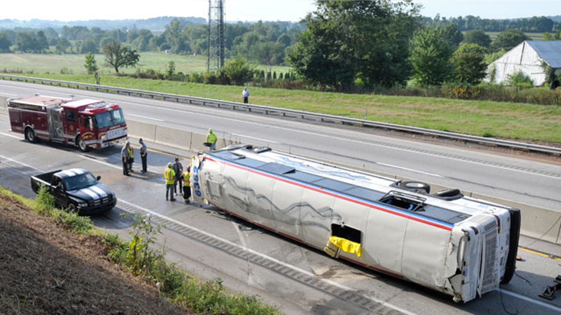 Emergency personnel work the scene where a Greyhound bus bound for St. Louis from New York City flipped on its side on the Pennsylvania Turnpike, briefly trapping a woman and injuring about two dozen people, according to authorities, about one mile east of the Lancaster-Lebanon interchange, early Saturday, Aug. 13, 2011, near Manheim, Pa.