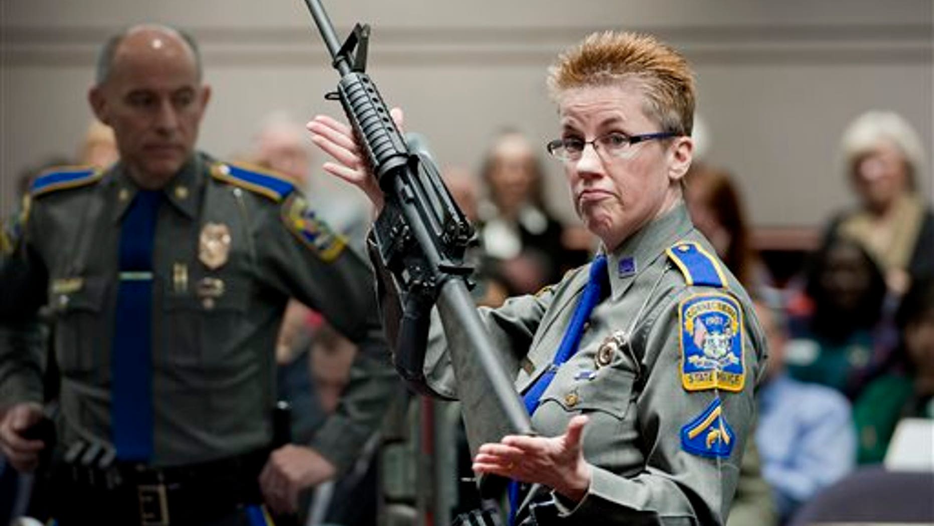 In this Jan. 28, 2013, file photo, firearms training unit Detective Barbara J. Mattson, of the Connecticut State Police, holds up a Bushmaster AR-15 rifle, the same make and model of gun used by Adam Lanza in the Sandy Hook School shooting, for a demonstration during a hearing of a legislative subcommittee reviewing gun laws, at the Legislative Office Building in Hartford, Conn.