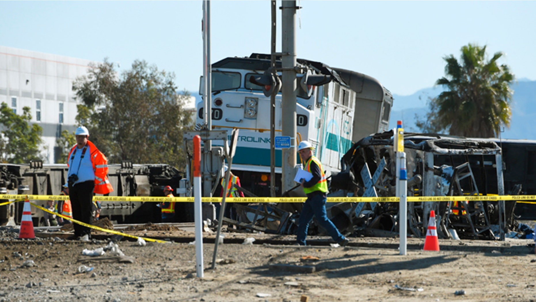 Workers walk near a Metrolink train engine from a train that hit a truck and then derailed Tuesday, Feb. 24, 2015, in Oxnard, Calif. Three cars of the Metrolink train tumbled onto their sides, injuring dozens of people in the town 65 miles northwest of Los Angeles. (AP Photo/Mark J. Terrill)