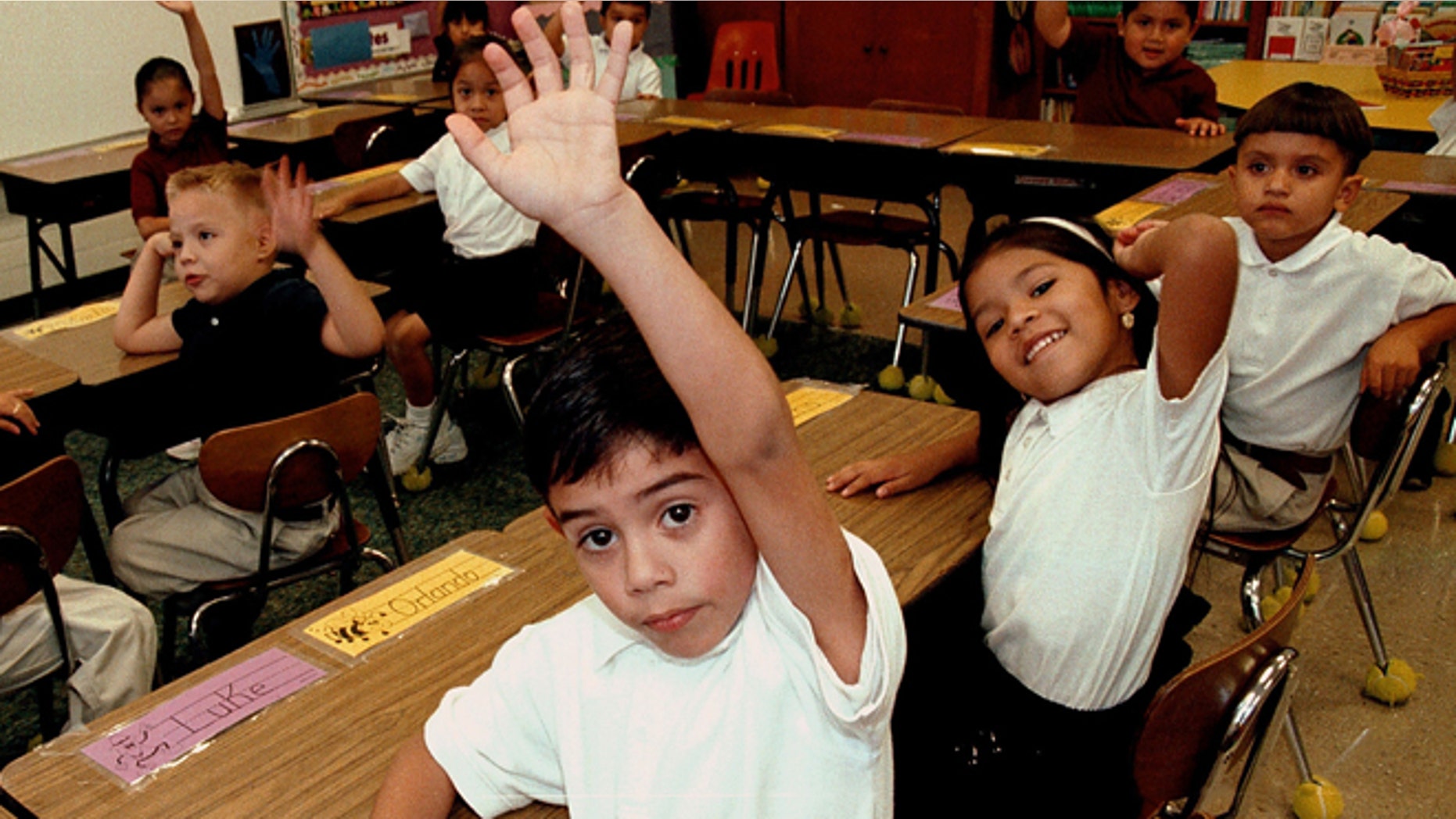 TYLER,TX - SEPTEMBER 11: Monolingual Hispanic students raise their hands to answer a question during a class taught in Spanish at Birdwell Elementary School September 11, 2003 in Tyler, Texas. The first grade students spend half their school day learning reading, writing, and arithmetic in Spanish and the other half learning them in English. Birdwell, a school of 600 students, 60 percent of them Hispanic with a significant portion of them Spanish speakers, requires a dual-language curriculum for it?s kindergarten and first graders. (Photo by Mario Villafuerte/Getty Images)