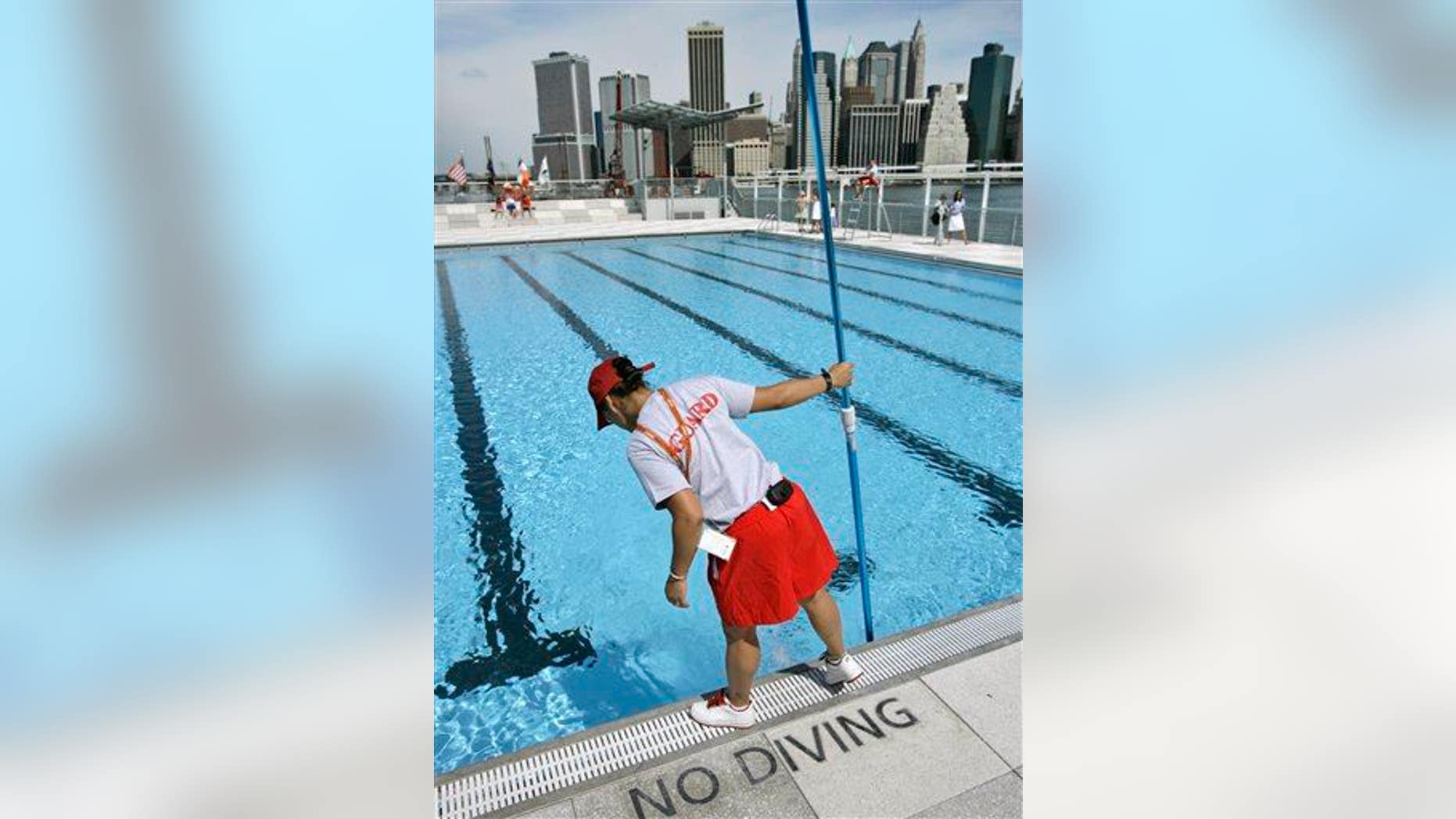 A lifeguard cleans the water at a swimming pool located on a barge anchored on Brooklyn's waterfront.