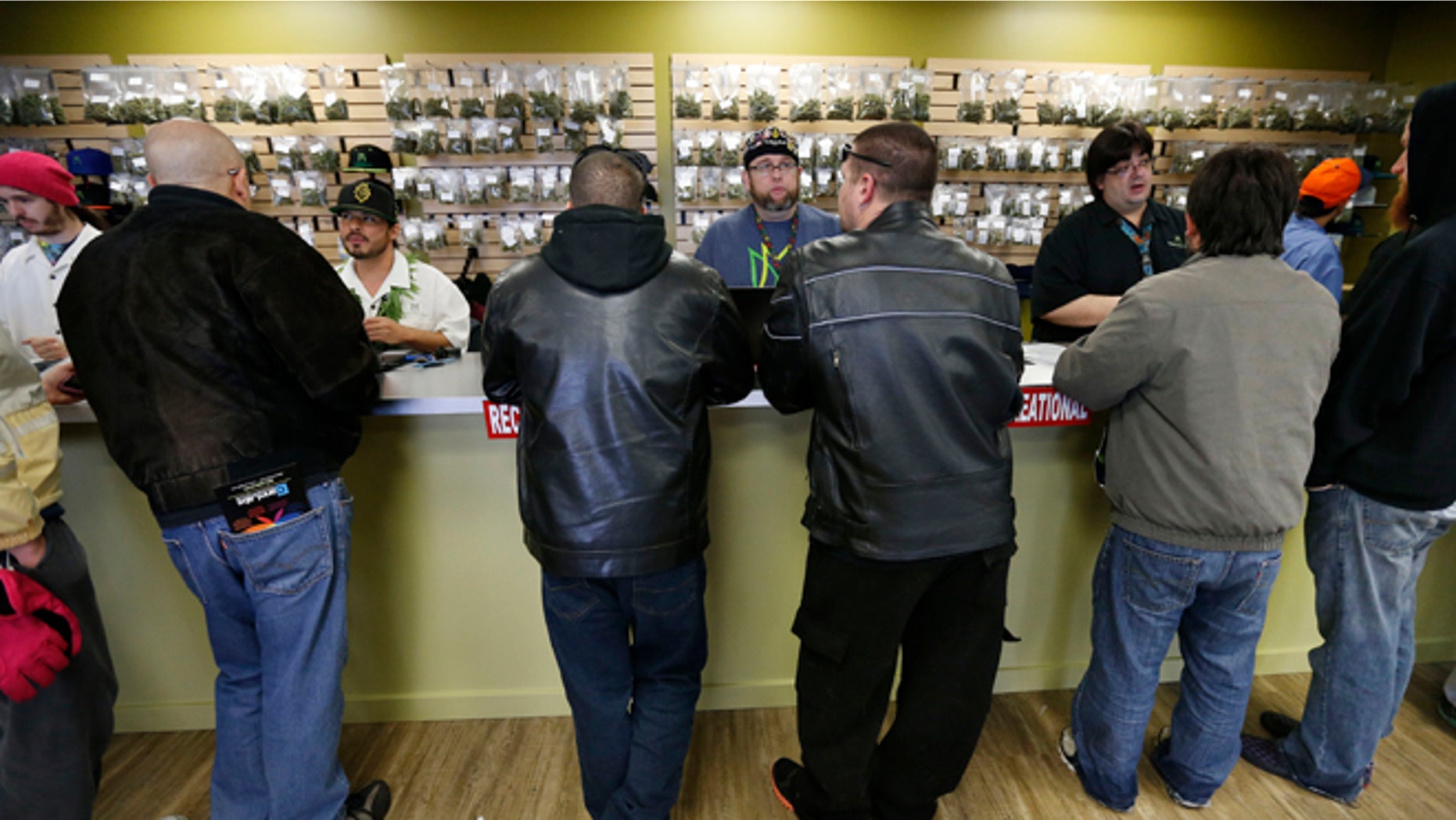 Employees help customers at the crowded sales counter inside Medicine Man marijuana retail store, which opened as a legal recreational retail outlet in Denver on Wednesday Jan. 1, 2014. Colorado began retail marijuana sales on Jan. 1, a day some are calling "Green Wednesday." (AP Photo/Brennan Linsley)