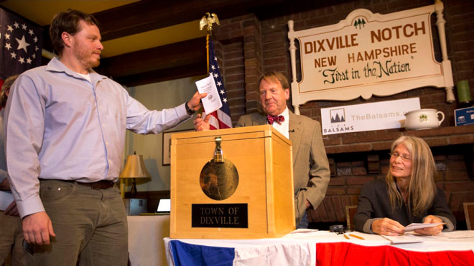 CORRECTS TO DIXVILLE NOTCH FROM DIXVILLE NOTCHE AND CLARIFIES VOTES- Dixville Notch's first voter Clay Smith drops his ballot into the box as moderator Tom Tillotson watches Tuesday, Nov. 8, 2016, in Dixville Notch, N.H. Dixville Notch, where the nation's first voters cast their ballots on Election Day, had Democratic presidential candidate Hillary Clinton beating Republican Donald Trump. (AP Photo/Jim Cole)