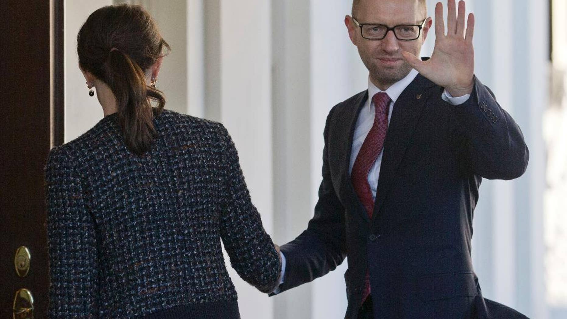 CORRECTS PHOTOGRAPHER TO PABLO MARTINEZ MONSIVAIS Ukraine Prime Minister Arseniy, right, waves as he is greeted by US acting Chief of Protocol Natalie Jones, left, during his arrival at the White House in Washington, Thursday, March 13, 2014. Arseniy is meeting with Vice President Joe Biden before traveling to New York to visit the United Nations. (AP Photo/Pablo Martinez Monsivais)