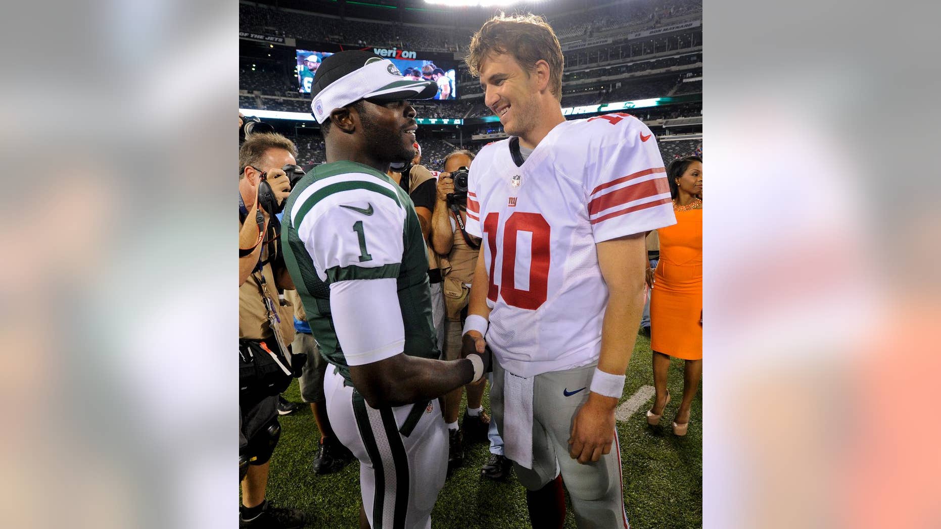 CORRECTS DAY AND DATE - New York Jets quarterback Michael Vick (1) talks with New York Giants quarterback Eli Manning (10) after a preseason NFL football game, Friday, Aug. 22, 2014, in East Rutherford, N.J. The Giants won 35-24. (AP Photo/Bill Kostroun)