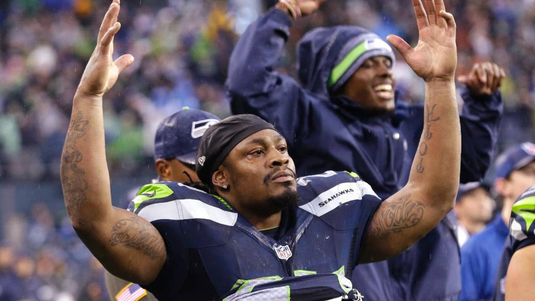 CORRECTS TO WILSON GAINING A FIRST DOWN, NOT SCORING A TOUCHDOWN - Seattle Seahawks running back Marshawn Lynch (24) gestures as Seahawks quarterback Russell Wilson runs for a first down against the New York Giants in the second half of an NFL football game, Sunday, Nov. 9, 2014, in Seattle. The Seahawks scored a touchdown on the drive. (AP Photo/Elaine Thompson)