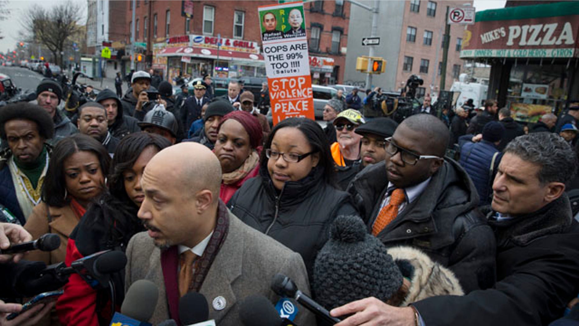 Dec. 22, 2014: Emerald Garner, daughter of Eric Garner, center, stands with National Action Network members near a makeshift memorial at the site where New York Police Department officers Rafael Ramos and Wenjian Liu were murdered in the Brooklyn borough of New York. (AP Photo/John Minchillo)