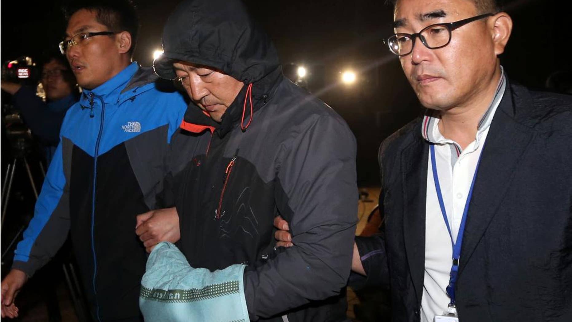 CORRECTS ID TO CREW MEMBER FROM CAPTAIN - Oh Yong-suck, center, a crew member of the sunken ferry Sewol in the water off the southern coast, leaves a court which issued his arrest warrant in Mokpo, south of Seoul, South Korea, Saturday, April 19, 2014. The investigation into South Korea's ferry disaster focused on the sharp turn it took just before it began listing and on the possibility that a quicker evacuation order by the captain could have saved lives, officials said Friday, as rescuers struggled to find some 270 people still missing and feared dead. (AP Photo/Yonhap) KOREA OUT
