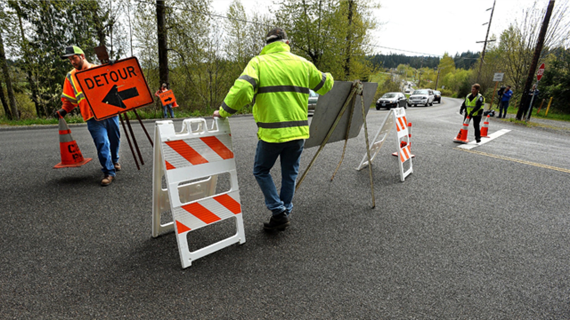April 13, 2015: Workers with the Bonney Lake Public Works Department set up signs along Sumner-Buckley Highway to divert traffic away from Angeline Road East in Bonney Lake, Wash., after three people were killed when a piece of concrete fell from an overpass onto a pickup truck in the roadway below. (David Montesino/The News Tribune via AP)