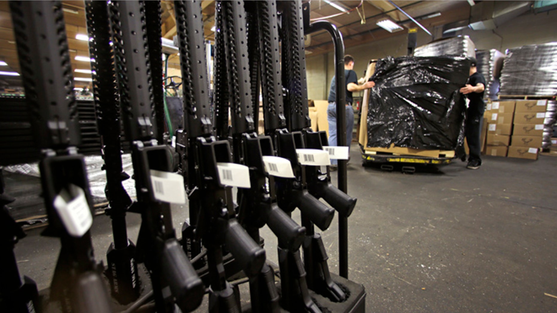 A rack of AR-15 rifles stand to be individually packaged as workers move a pallet of rifles for shipment at the Stag Arms company in New Britain, Conn., Wednesday, April 10, 2013.
