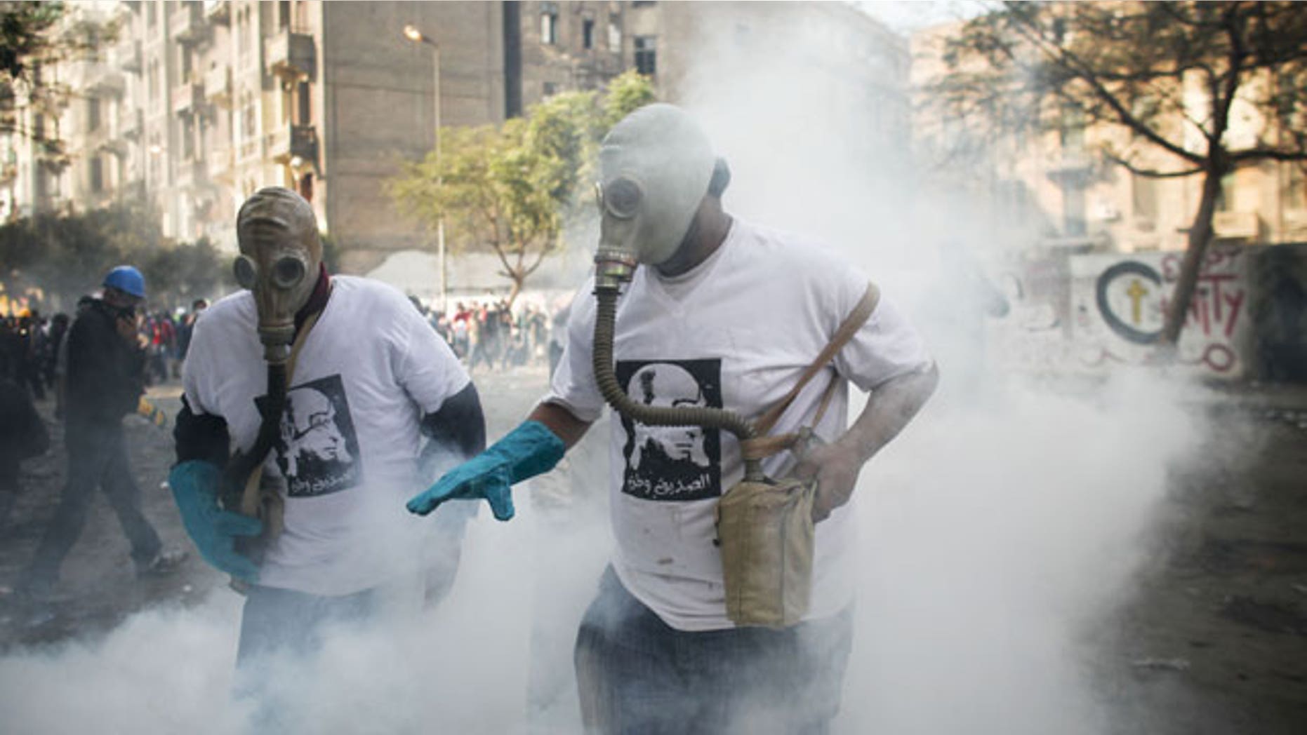 November 23, 2011: Protesters attempt to get rid of a tear gas canister during clashes with Egyptian riot police, not pictured, near Tahrir square in Cairo, Egypt.