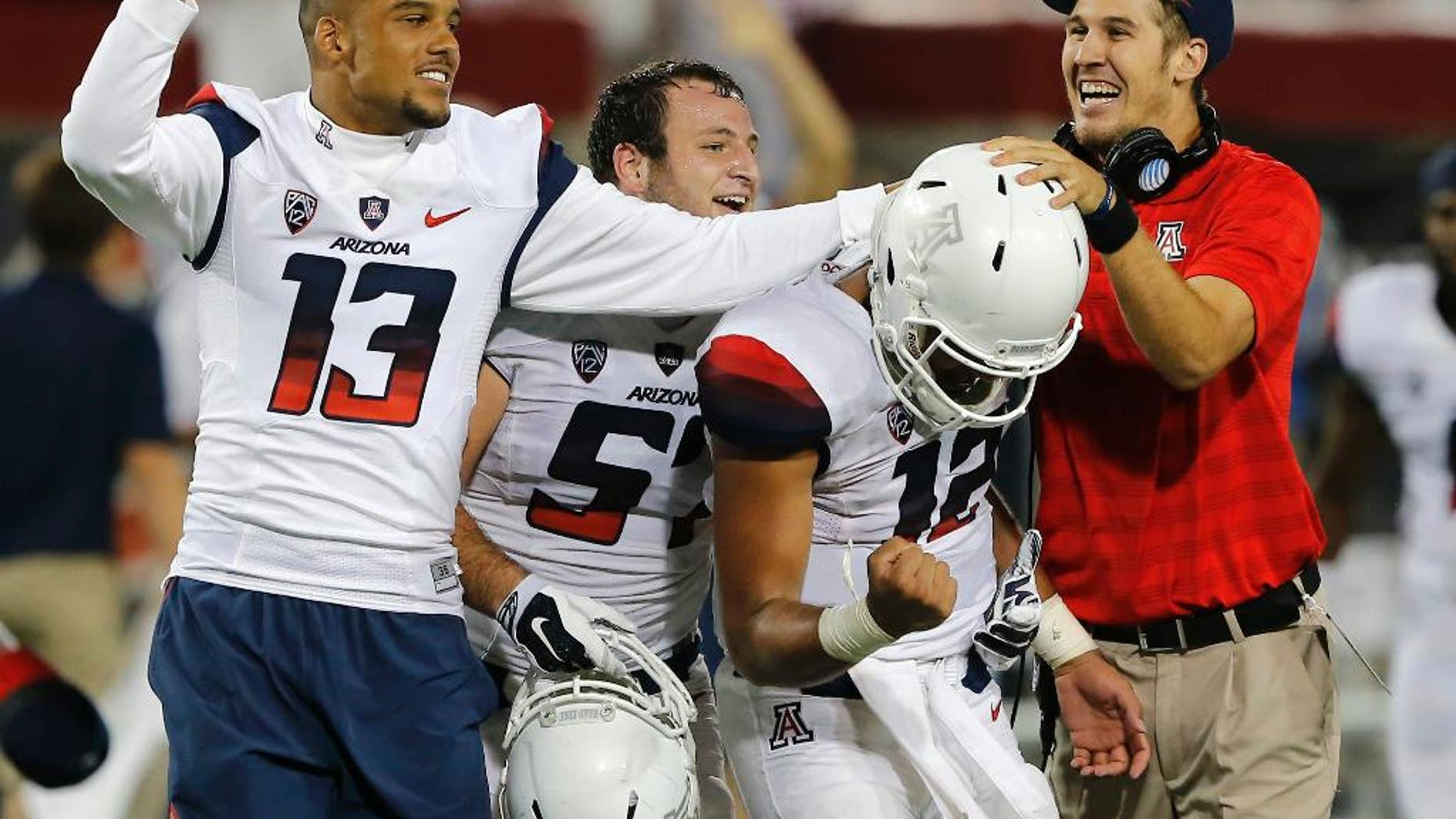 Arizona quarterback Anu Solomon (12) and Brandon Dawkins (13) celebrate after Solomon throws a hail mary touchdown during the second half of an NCAA college football game against California, Saturday, Sept. 20, 2014, in Tucson, Ariz. Arizona defeated California 49-45. (AP Photo/Rick Scuteri)