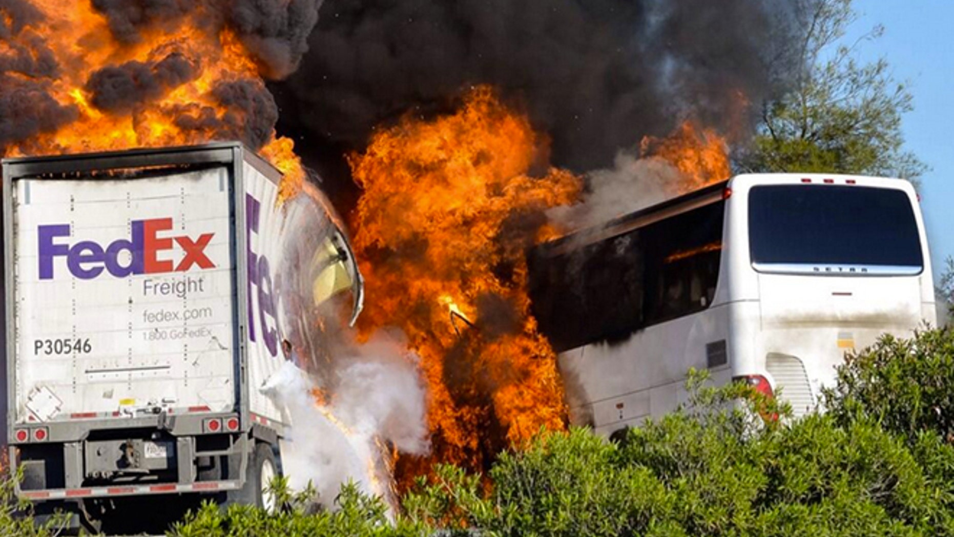 Massive flames are seen devouring both vehicles just after the crash, and clouds of smoke billowed into the sky Thursday April 10, 2014 until firefighters had quenched the fire, leaving behind scorched black hulks of metal. The FedEx tractor-trailer crossed a grassy freeway median in Northern California and slammed into the bus carrying high school students on a visit to a college. At least nine were killed in the fiery crash, authorities said. (AP Photo/Jeremy Lockett)