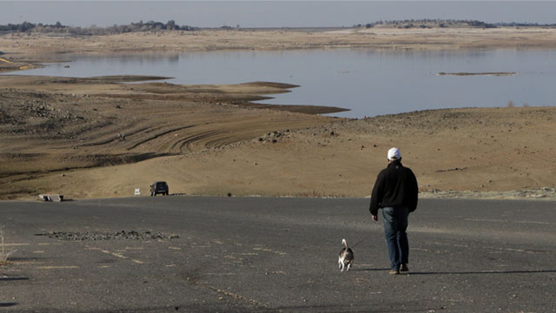 FILE -- In this Jan. 9, 2014 file photo a visitor to Folsom Lake, Calif., walks his dog down a boat ramp that is now several hundred yards away from the waters edge, in Folsom, Calif. Gov. Jerry Brown was governor the last time California had a drought of epic proportions, in 1975-76 and now is pushing a controversial $25 billion plan to build twin tunnels to ship water from the Sacramento-San Joaquin River Delta to farmland and cities further south. (AP Photo/Rich Pedroncelli,file)