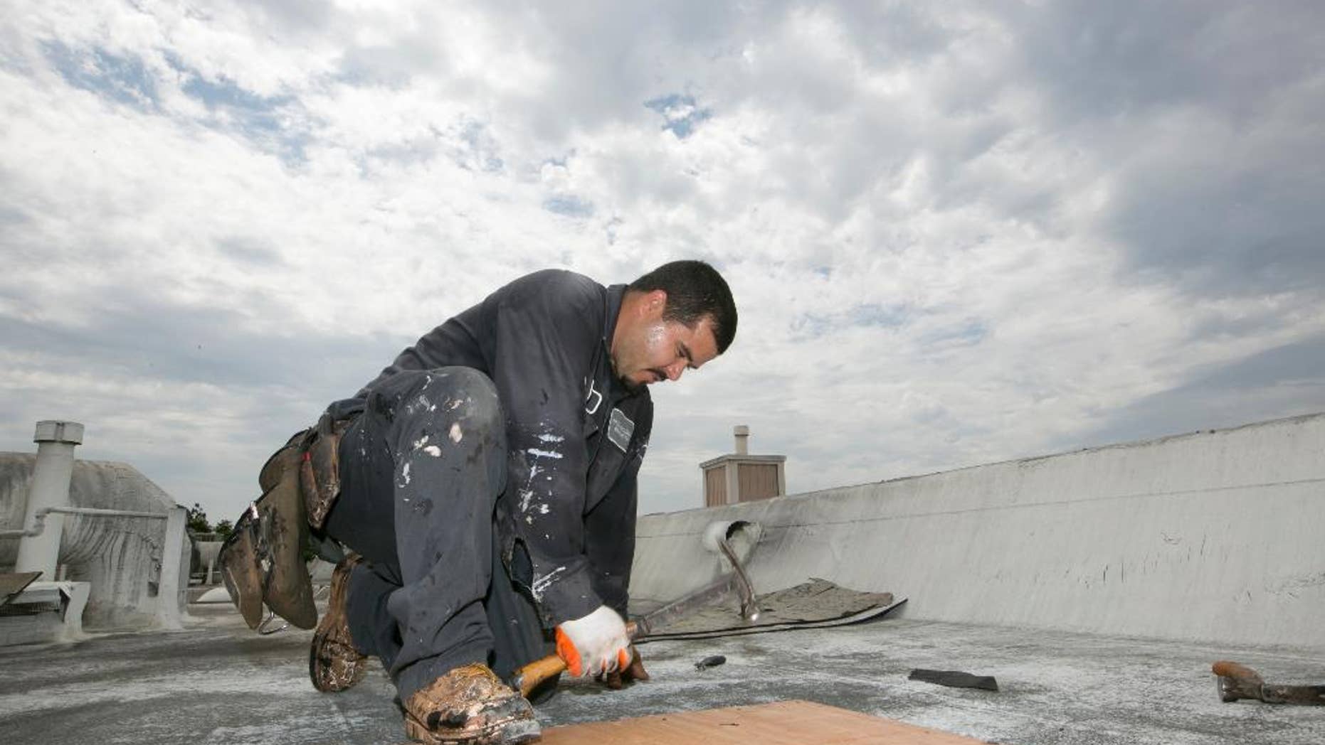 Roofer Joel Camberos with Hull Brothers Roofing & Waterproofing resurface townhomes roofs at the Marina del Rey seaside community of Los Angeles on Tuesday, Aug. 25, 2015. Roofers are reveling in the uptick in business as homeowners ready for the prospect of downpours after four years of dry weather. (AP Photo/Damian Dovarganes)