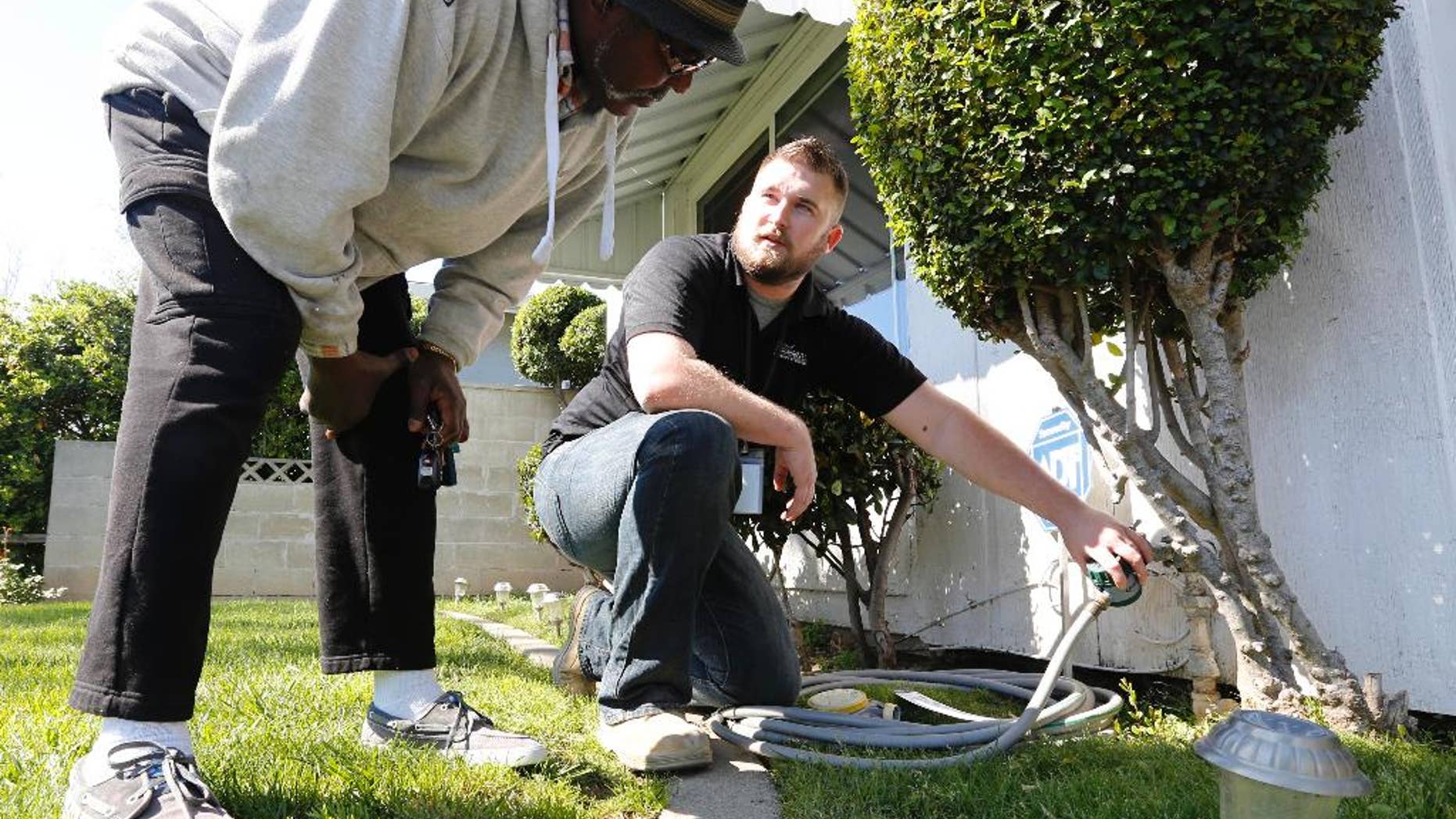 FILE -- In this March 11, 2014 file photo Steve Upton, right, demonstrates how to use the water timer he installed on the water spigot at the home of Larry Barber, left, in Sacramento, Calif. Upton, an inspector for the water conservation unit of the Sacramento Utilities Department, follows up on tips concerning city residents wasting water in one of California's driest years on record. (AP Photo/Rich Pedroncelli,file)