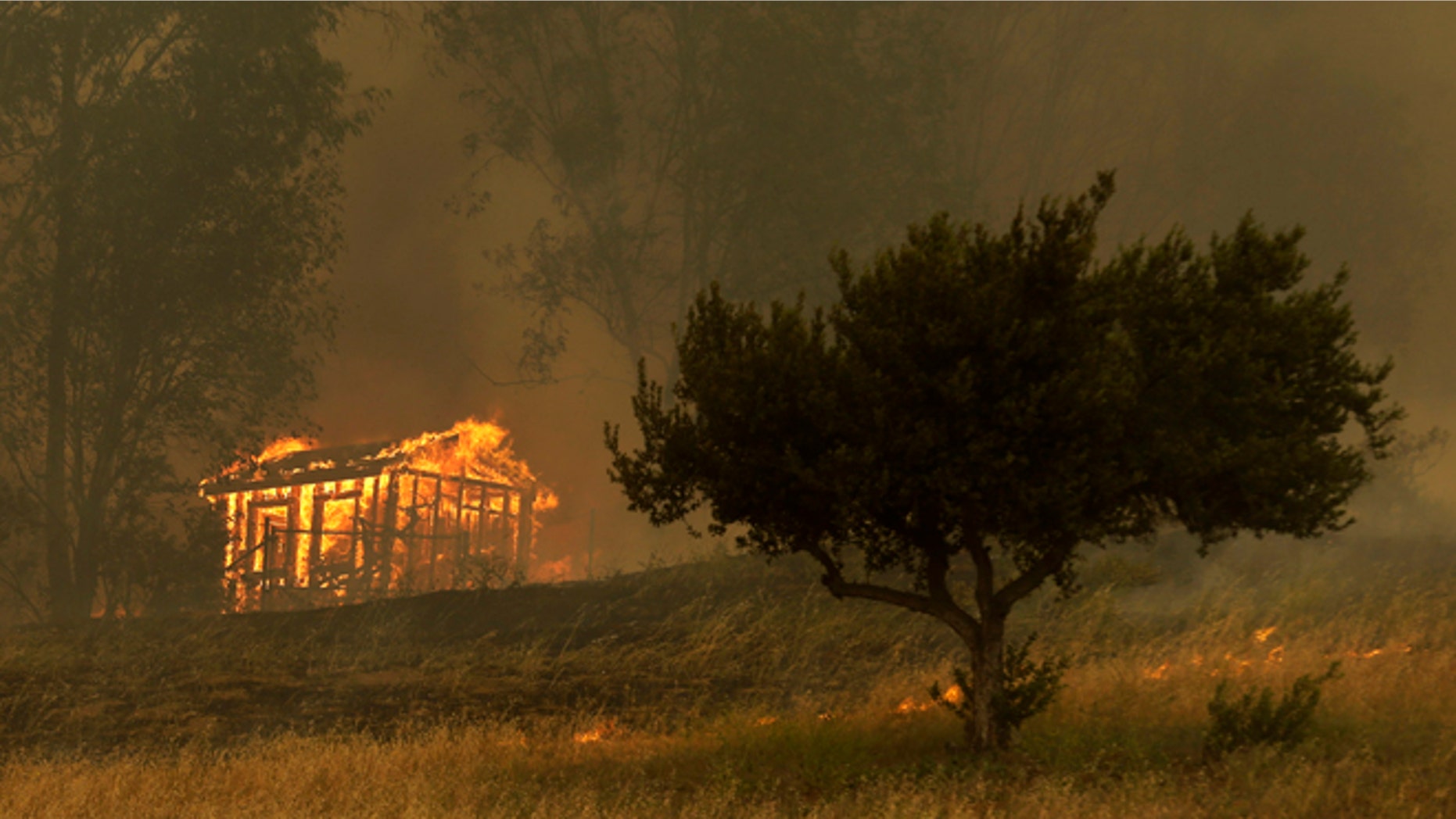 Fire engulfs a structure during a wildfire Thursday, May 15, 2014, in Escondido, Calif. One of the nine fires burning in San Diego County suddenly flared Thursday afternoon and burned close to homes, trigging thousands of new evacuation orders. (AP Photo/Gregory Bull)