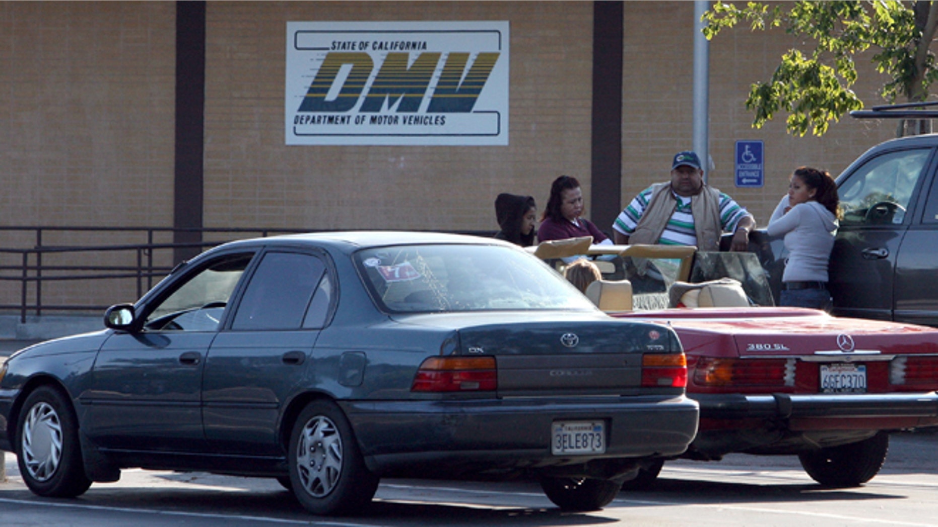 California Department of Motor Vehicles customers sit in the parking lot after finding out that the DMV is closed in Corte Madera, California. (Photo by Justin Sullivan/Getty Images)