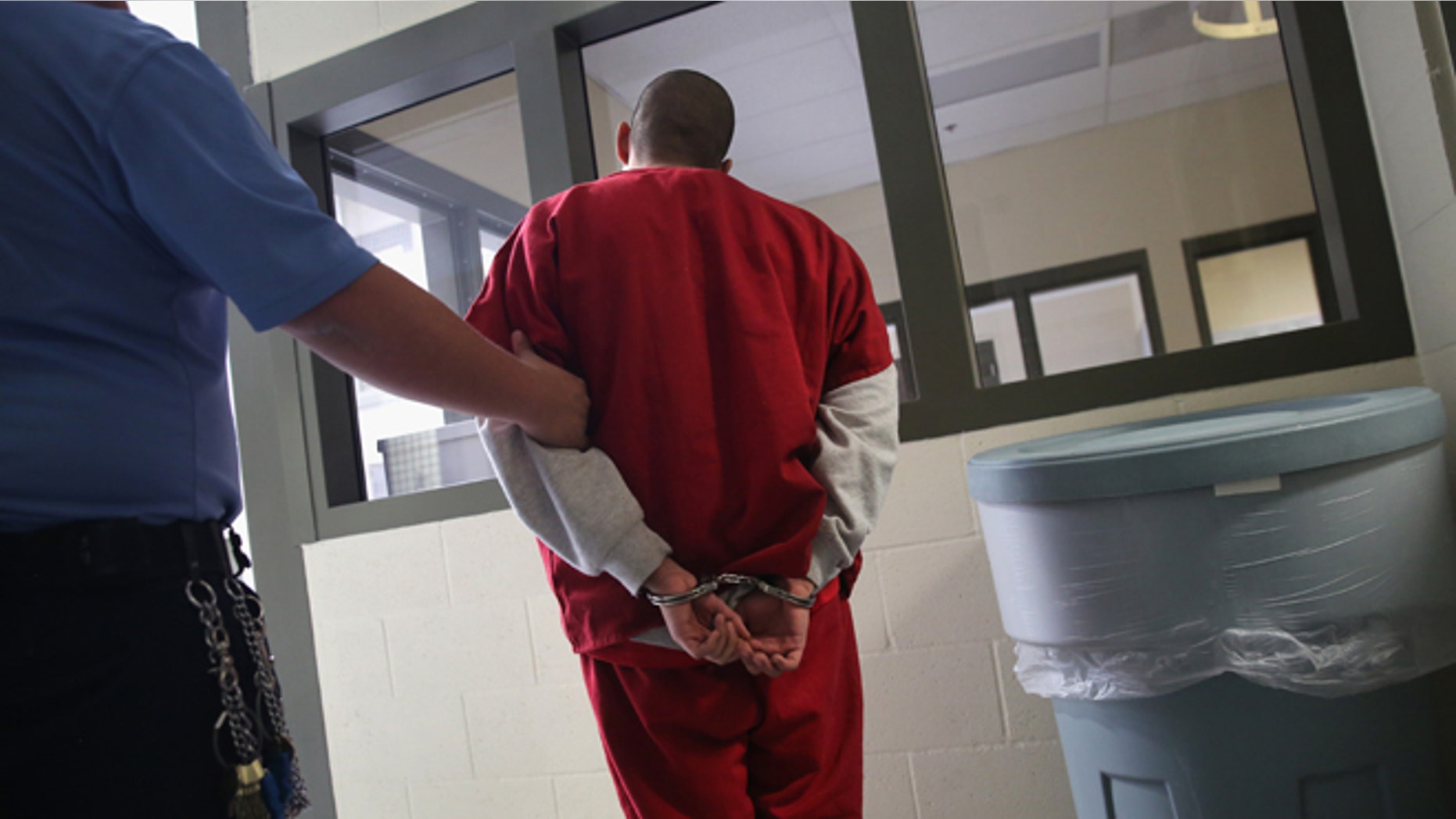 ADELANTO, CA - NOVEMBER 15: A guard escorts an immigrant detainee from his 'segregation cell' back into the general population at the Adelanto Detention Facility on November 15, 2013 in Adelanto, California. Most detainees in segregation cells are sent there for fighting with other immigrants, according to guards. The facility, the largest and newest Immigration and Customs Enforcement (ICE), detention center in California, houses an average of 1,100 immigrants in custody pending a decision in their immigration cases or awaiting deportation. The average stay for a detainee is 29 days. The facility is managed by the private GEO Group. ICE detains an average of 33,000 undocumented immigrants in more than 400 facilities nationwide. (Photo by John Moore/Getty Images)