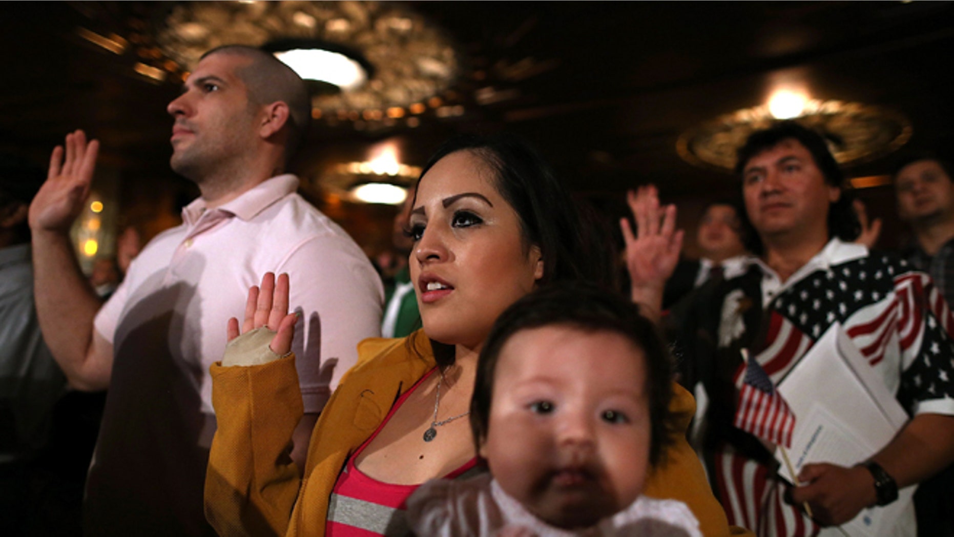 OAKLAND, CA - JULY 30: Karen Franco of Peru holds her four-month old daughter Kyara Franco as she is sworn in as a U.S. citizen during a naturalization ceremony at the Paramount Theatre on July 30, 2013 in Oakland, California. Over 1,100 immigrants became U.S. citizens at the naturalization ceremony. (Photo by Justin Sullivan/Getty Images)
