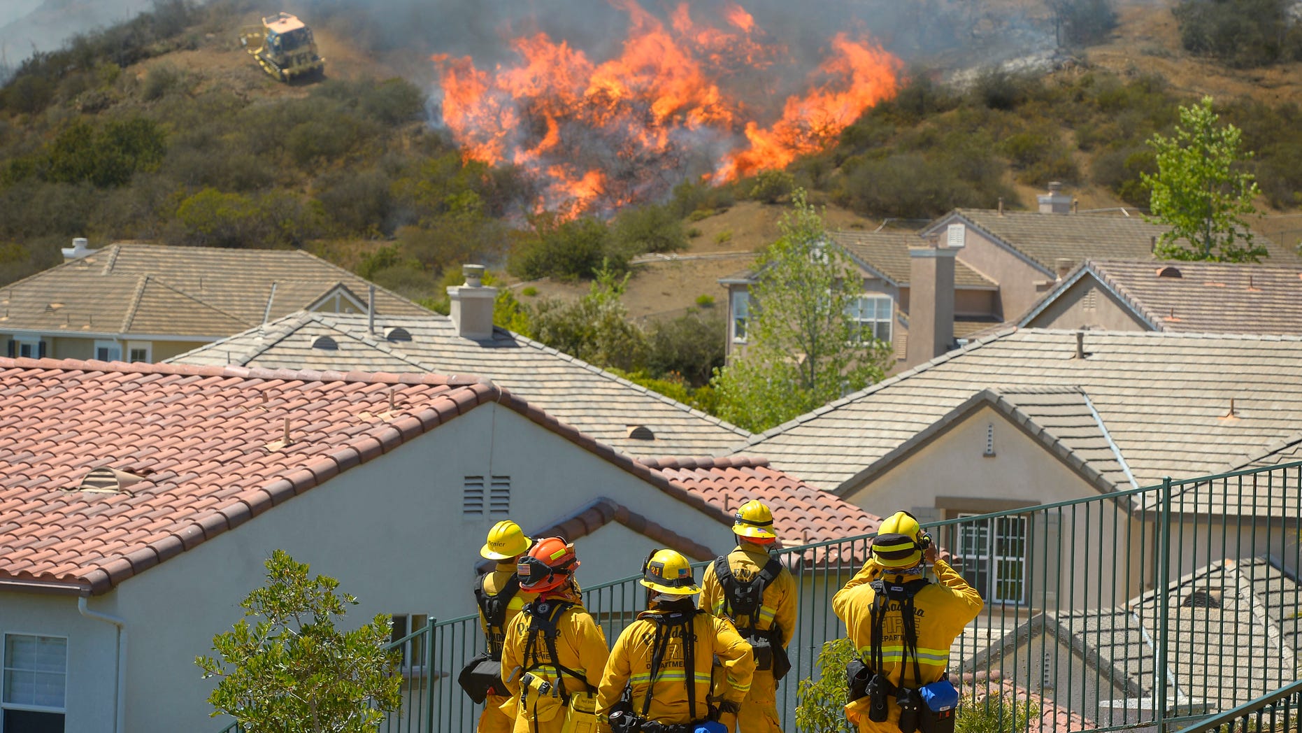 Firefighters from Glendale, Calif., and Pasadena, Calif., stand watch as bulldozers clear a firebreak near a wildfire burning along a hillside near homes in Thousand Oaks, Calif., Thursday, May 2, 2013.