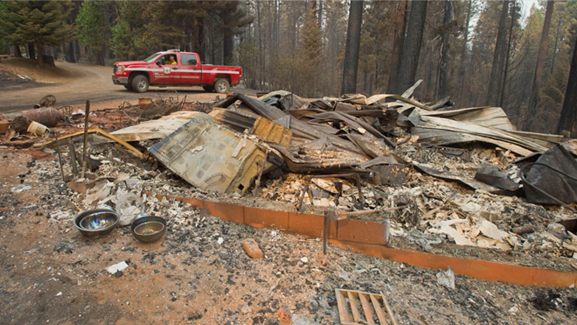 In a Friday, Sept. 19, 2014 file photo, a truck passes one of several homes that burned in the recent King fire near Icehouse in El Dorado County, Calif. Officials said Sunday, Sept. 21, 2014, that nearly three-dozen structures were destroyed in the massive Northern California wildfire that continues to spread more than a week after it started.