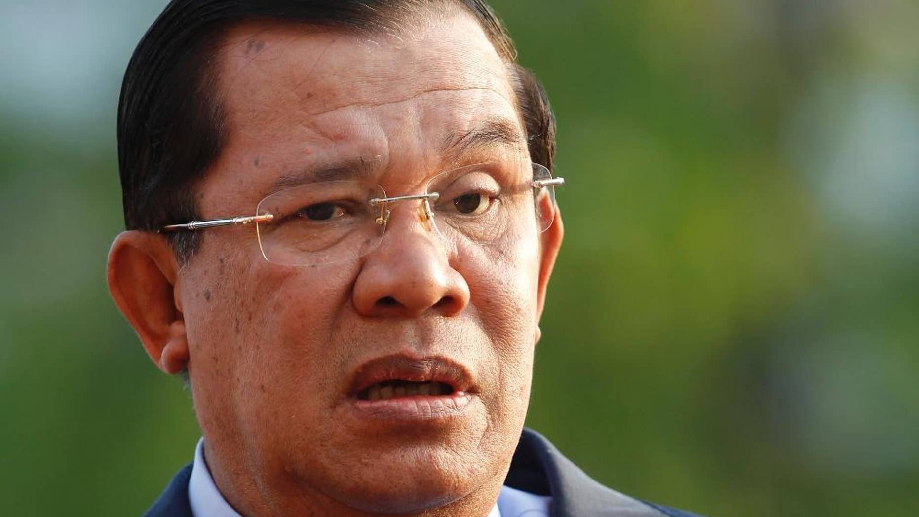 In this Jan. 7, 2015 photo, Cambodian Prime Minister Hun Sen talks with top leaders of his party before an event by the ruling Cambodian People's Party marking the 36th anniversary of the 1979 downfall of the Khmer Rouge regime at their party headquarters in Phnom Penh, Cambodia. Construction of a massive dam in southwestern Cambodia will not start until at least 2018, Prime Minister Hun Sen said Tuesday, Feb. 24, 2015 in an apparent effort to stop heavy opposition to the project which has focused criticism on him. (AP Photo/Heng Sinith)