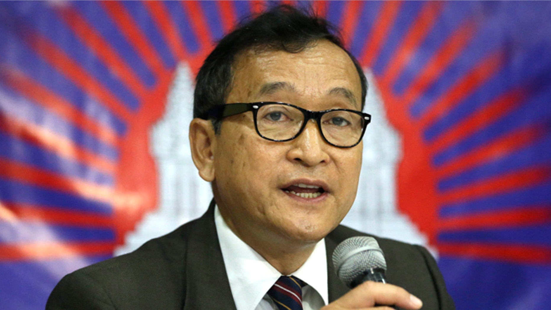 In this Sept. 10, 2012 file photo, Cambodian opposition leader Sam Rainsy, who was currently living in exile in France, talks about the opposition's plans for 2013 elections in Cambodia during the launching of the International Parliamentary Committee for Democratic Elections in Cambodia with Philippine Sen. Franklin Drilon in San Juan, east of Manila, Philippines.