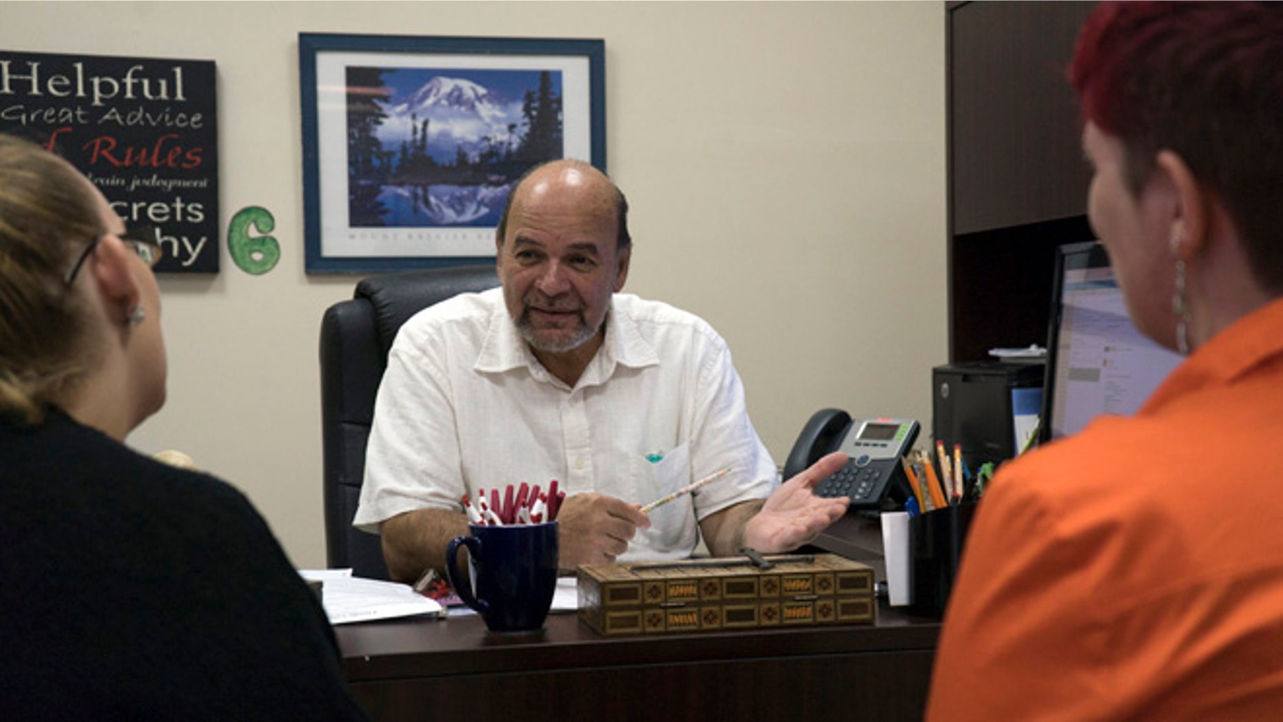 Reverend and Puerto Rican community organization director Robertoluis Lugo Morciglio talks with his colleagues in his office on Friday, Aug.12, 2016. With Puerto Rico's economy in shambles, many are fleeing to the mainland U.S., potentially shifting demographics in some of the country's most critical battleground states. (AP Photo/Dake Kang)