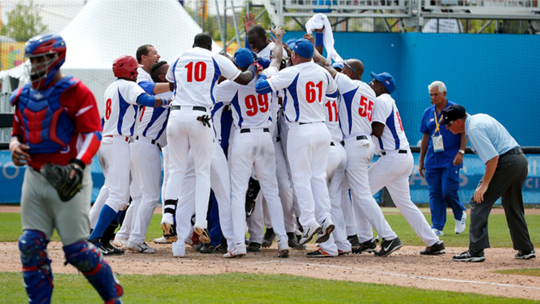 Cuba's Jose Garcia, top center, is mobbed by teammates after hitting a walk off home run off Puerto Rico pitcher Raul Rivera in the ninth inning of the bronze medal baseball game at the Pan Am Games, Sunday, July 19, 2015, in Ajax, Ontario. Cuba won 7-6. (AP Photo/Julio Cortez)