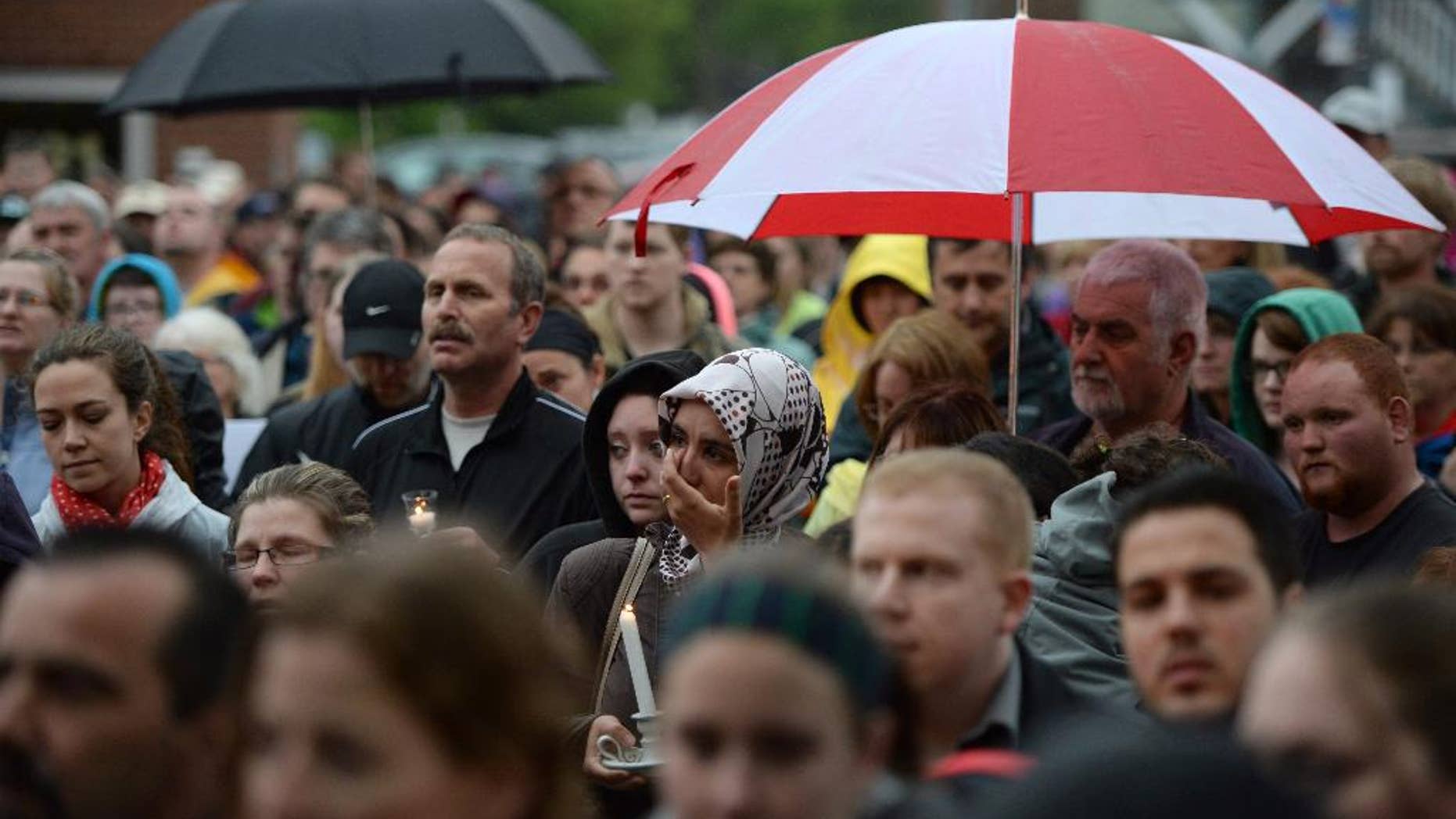 People take part in a candlelight vigil outside Royal Canadian Mounted Police headquarters in Moncton, New Brunswick, Canada on Friday, June 6, 2014. The RCMP say Justin Bourque, suspected in the shooting deaths of three Mounties and the wounding of two others in Moncton, was unarmed at the time of his arrest early Friday and was taken into custody without incident. (AP Photo/The Canadian Press, Sean Kilpatrick)