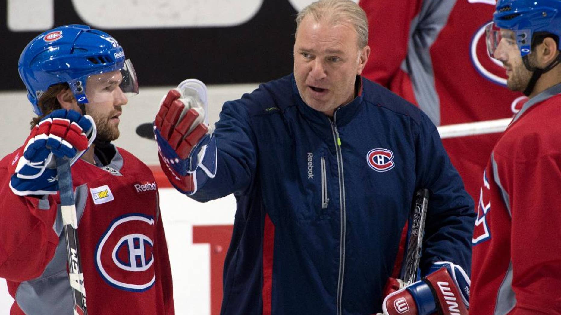 Montreal Canadiens head coach Michel Therrien goes over a play with Montreal Canadiens center David Desharnais, left, and left wing Max Pacioretty, right, during the team's NHL hockey practice Monday, April 28, 2014, in Brossard, Quebec. (AP Photo/The Canadian Press, Ryan Remiorz)