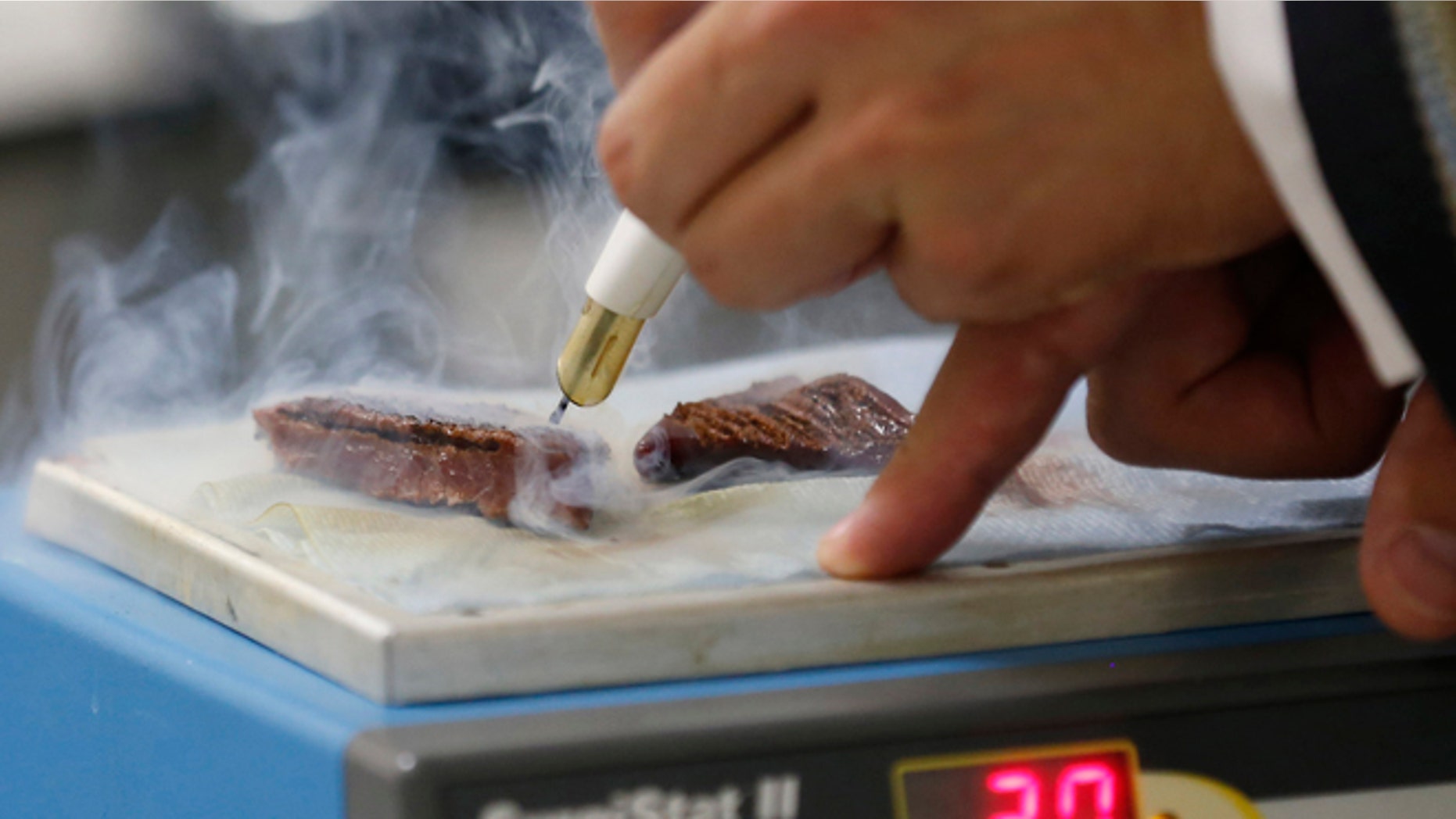 Dr James Kinross, lecturer in surgical metabonomics of Imperial College London uses the the experimental knife on a piece of animal muscle during a demonstration at St Mary's Hospital in London, Wednesday, July 17, 2013. Surgeons may have a new way to smoke out cancer. An experimental surgical knife can help surgeons make sure they've removed all the cancerous tissue, doctors reported Wednesday. Surgeons typically use knives that vaporize tumors as they cut, producing a sharp-smelling smoke. The new knife analyzes the smoke and can instantly signal whether the tissue is cancerous or healthy.(AP Photo/Sang Tan)